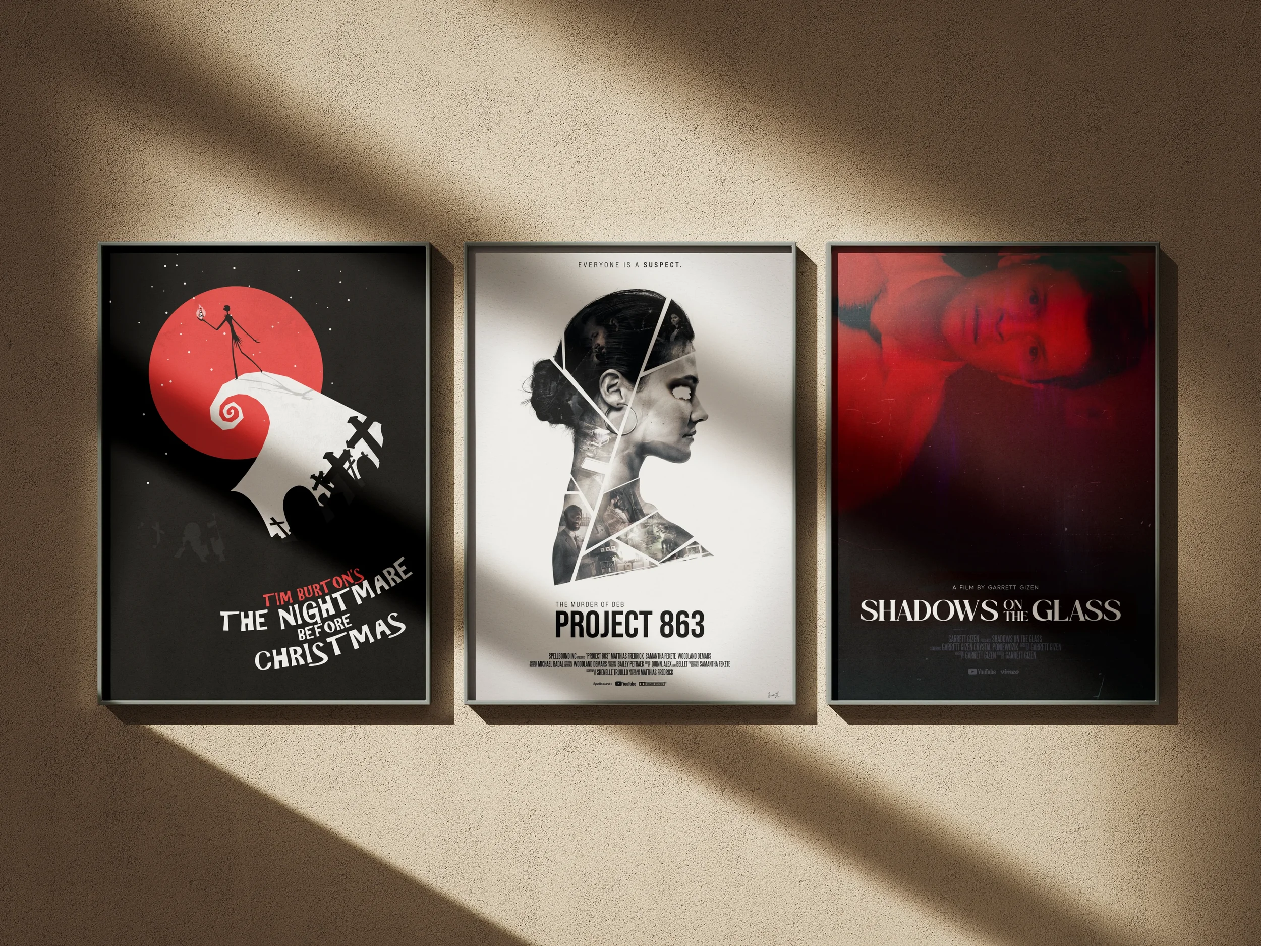 Three movie posters are displayed on a beige wall, with light casting shadows on the upper part of the wall. The left poster is for 'The Nightmare Before Christmas,' featuring a silhouette of Jack Skellington on a snowy hill with a red moon in the background. The middle poster is for 'Project 863,' showing a stylized profile of a woman with newspaper and photo collage elements and the quote 'Everyone is a suspect.' The right poster is for 'Shadows on the Glass,' featuring a woman with a blurred red-overlaid face.