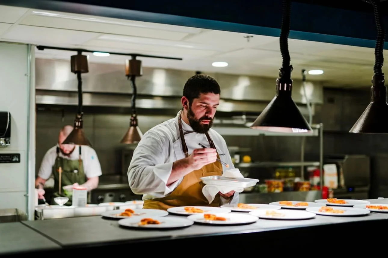 Chef garnishing plates of food in a professional kitchen.