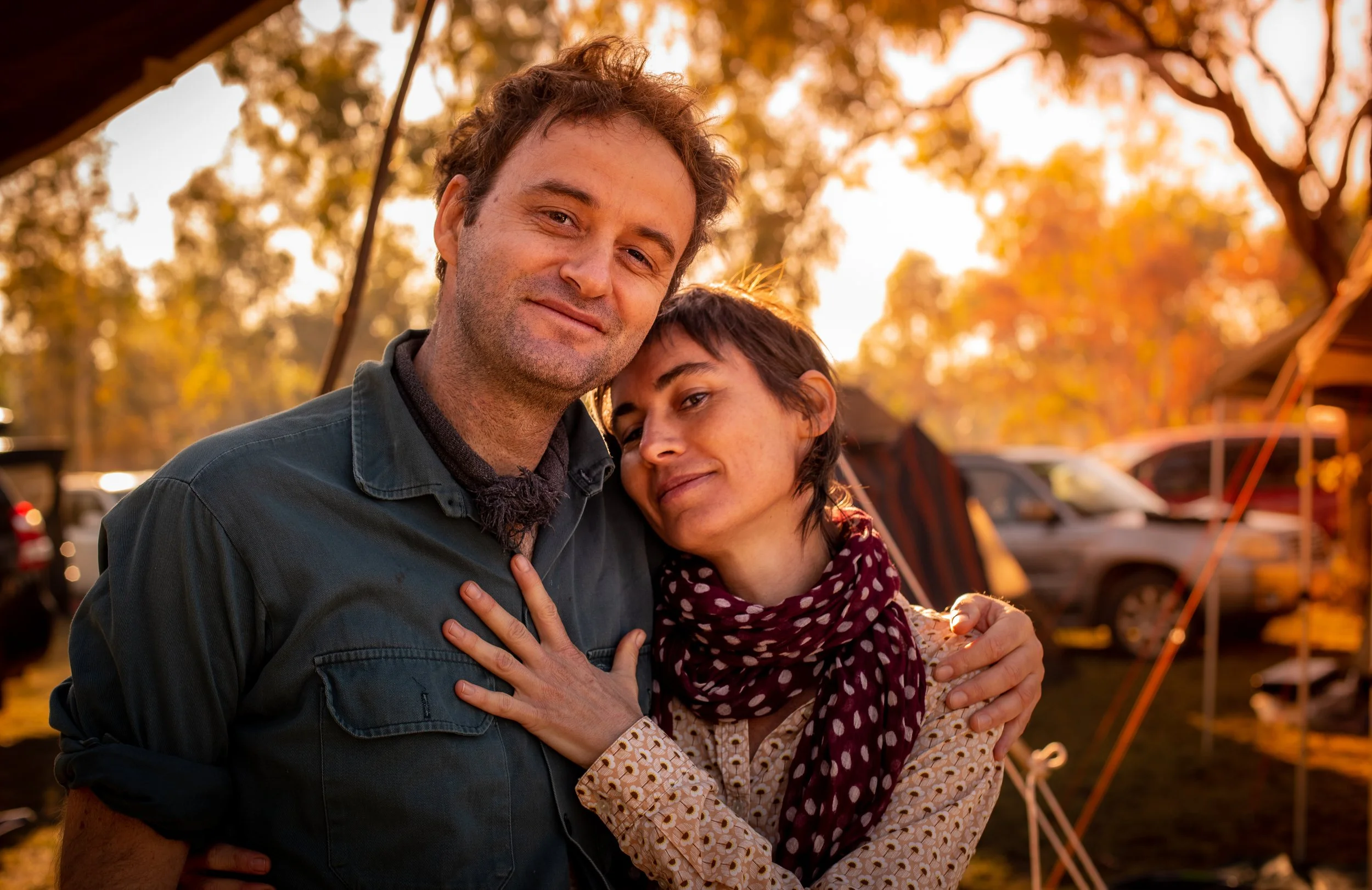 At the Barunga Festival in the Northern Territory, a couple embraces outdoors, smiling at the camera with sunset in the background.