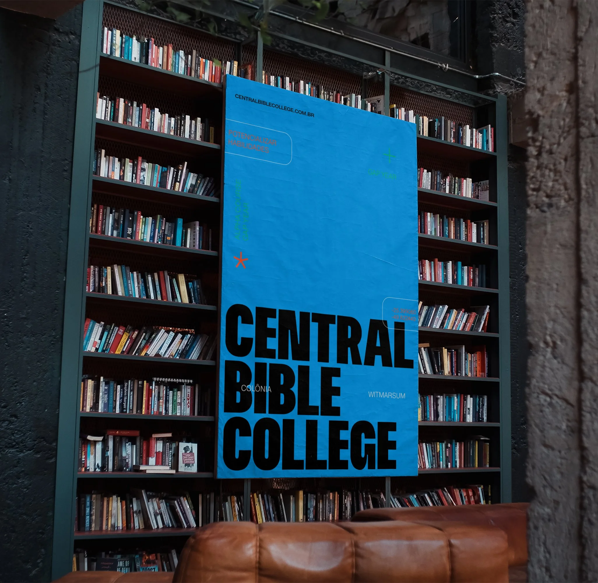 Large blue vertical banner with black text stating 'Central Bible College,' hanging in front of bookshelves filled with various books, in an interior space with dark walls and a leather couch in the foreground.