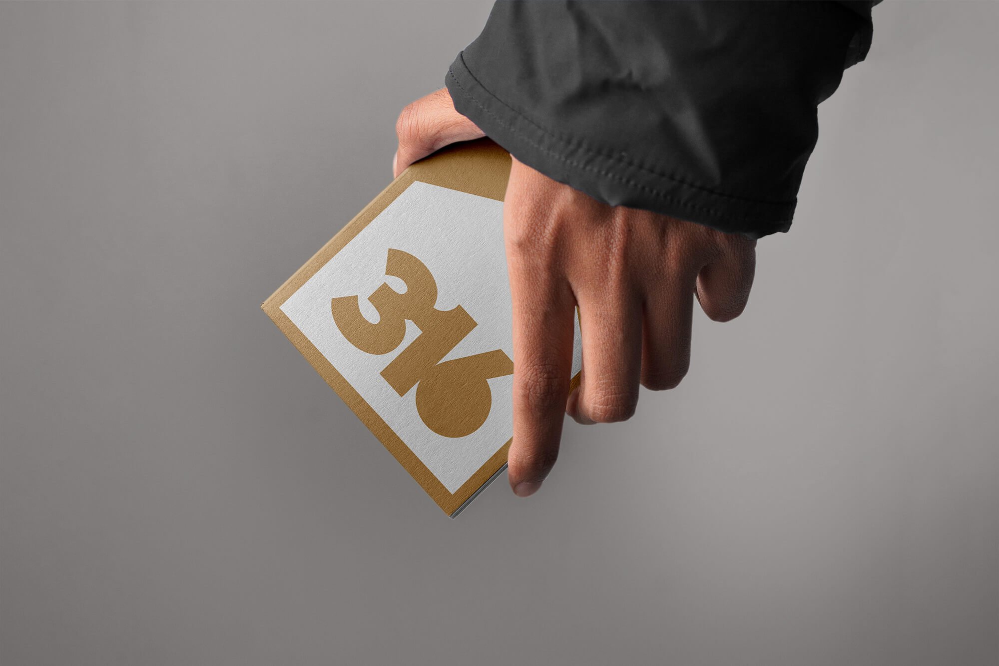 Person holding a brown and white large playing card with the number 3 and a heart symbol, with the index finger pointing down.