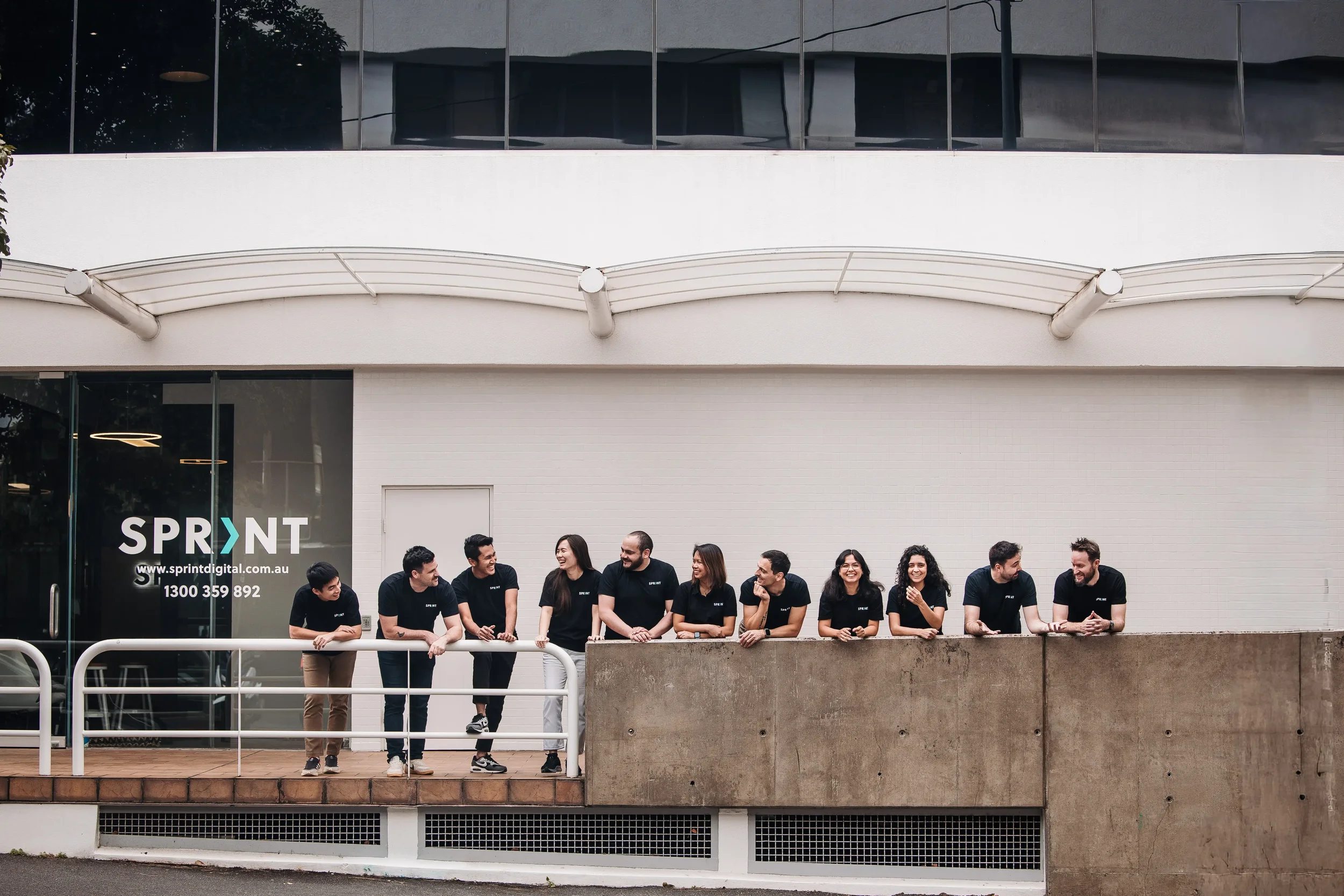 Sprint team in front of the office lining  up next to each other.