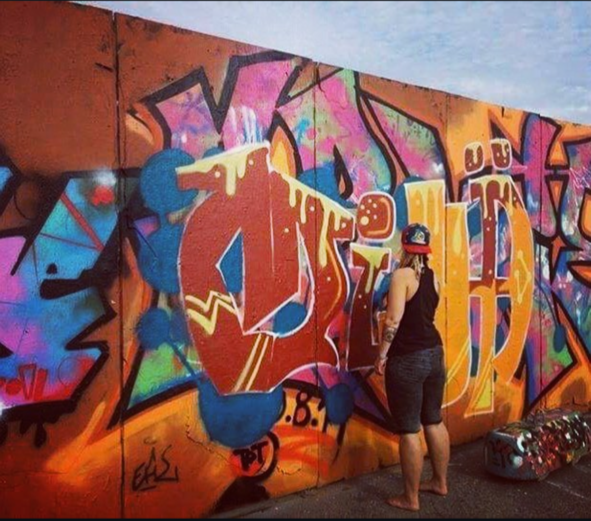 ihminen maalaa värikästä graffitia