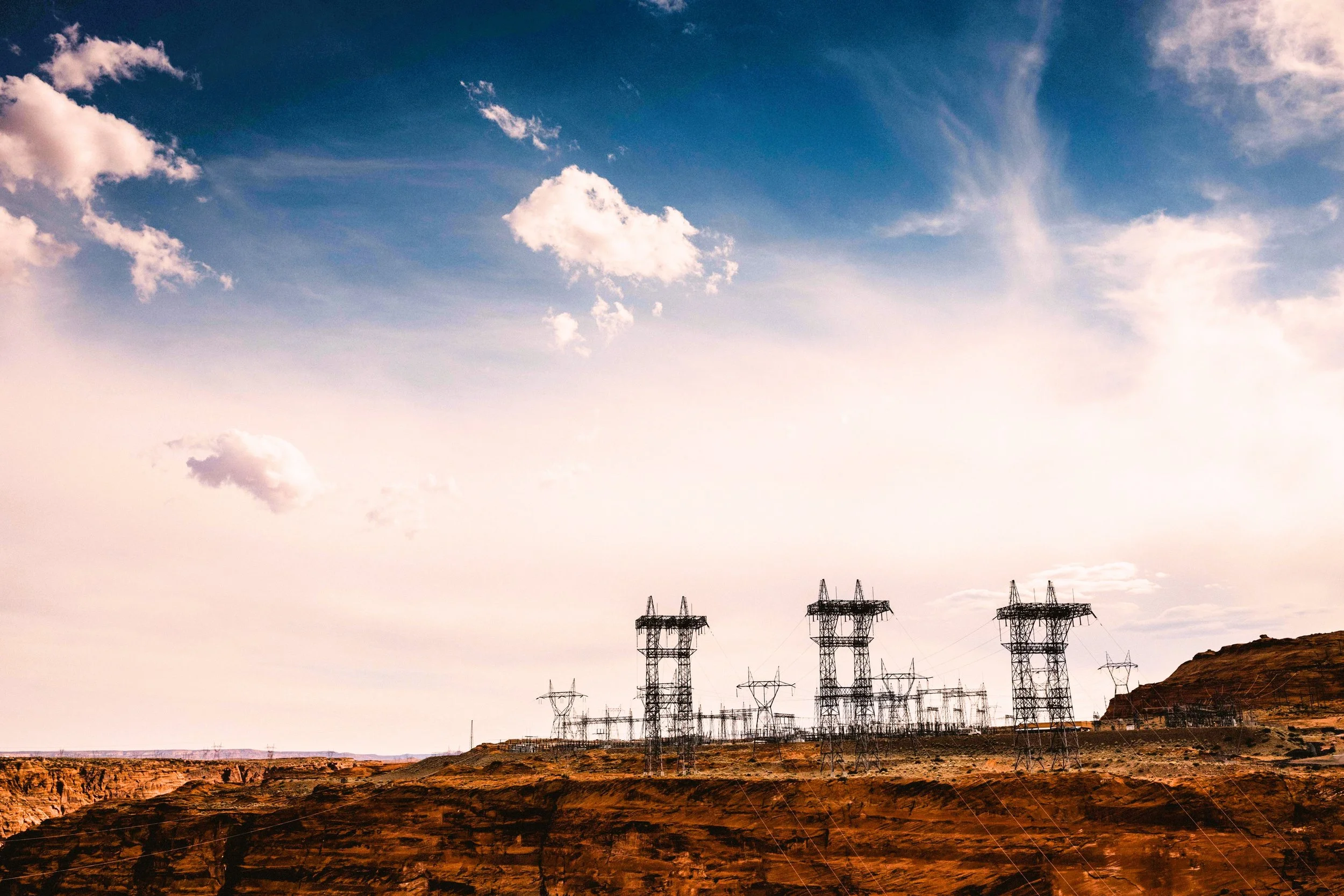 Electrical substation and high-voltage transmission towers on arid red-rock terrain, remote power infrastructure