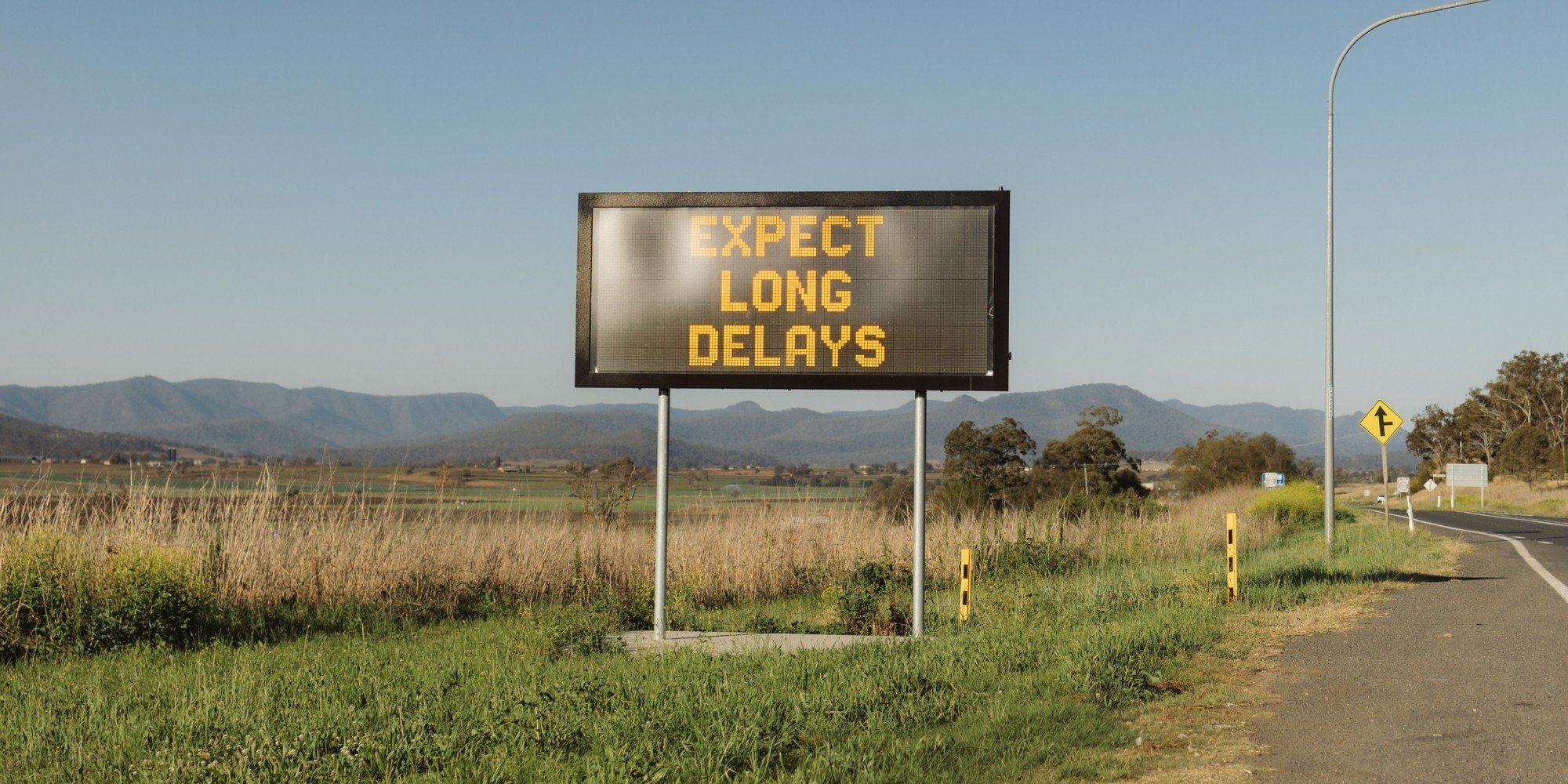Roadside electronic sign reading Expect Long Delays on a rural Australian highway near Gladfield, Queensland.
