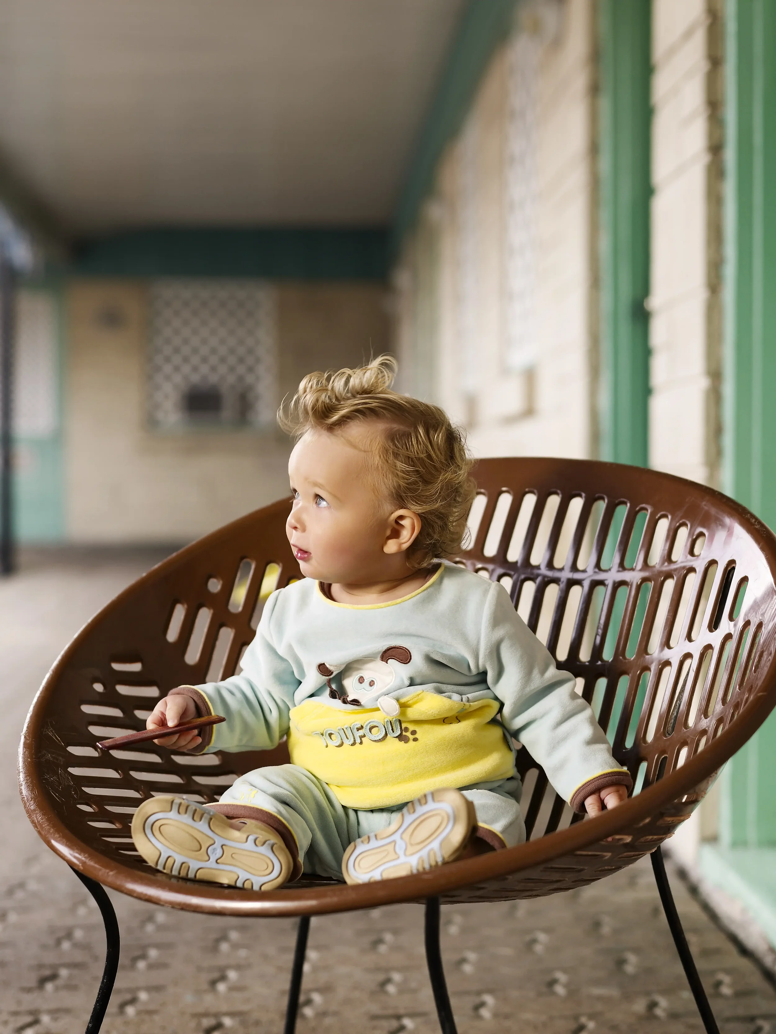 ébé coiffé dans un style années 60 assis dans un fauteuil vintage dans le couloir d’un motel américain