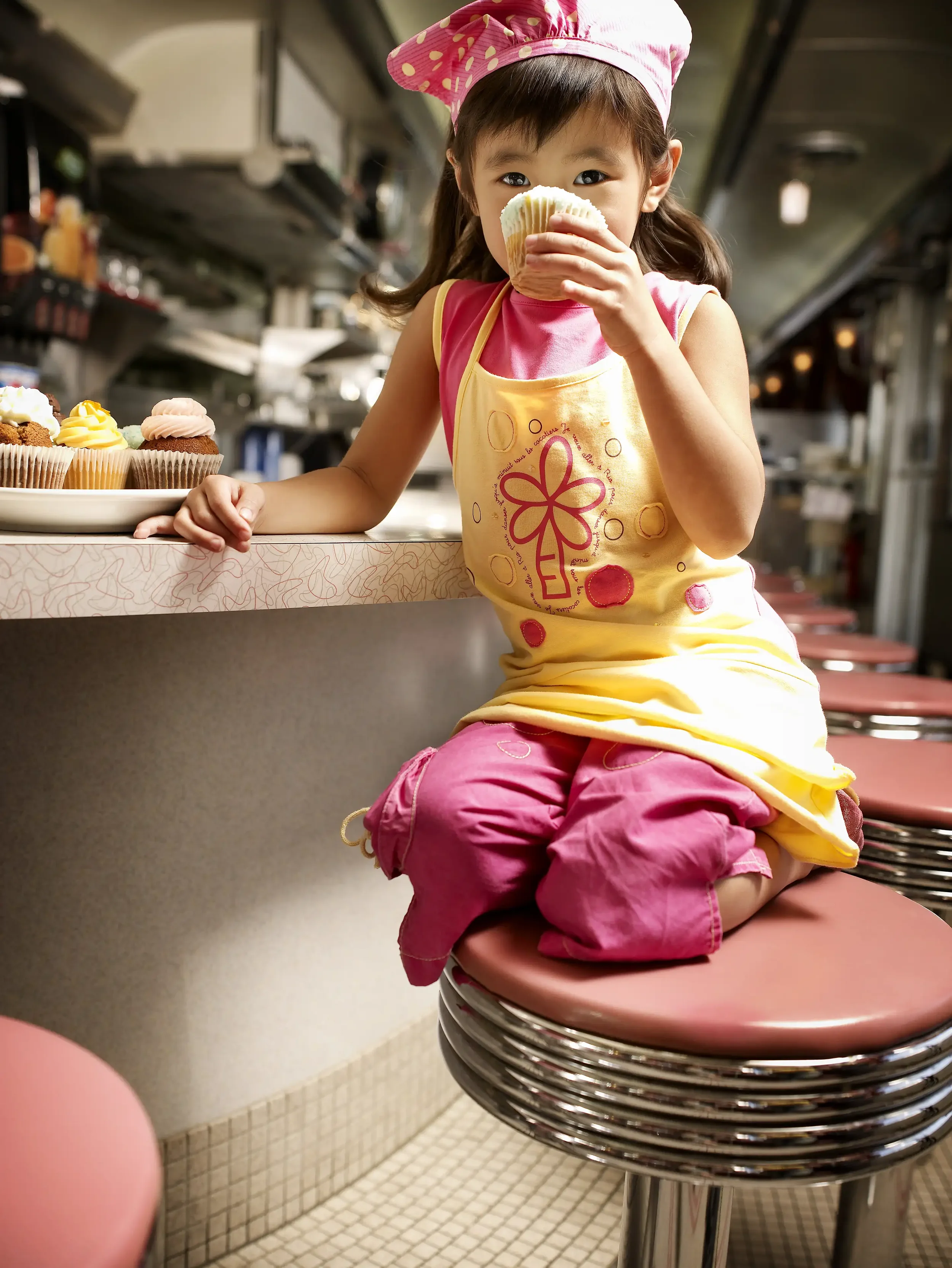 Portrait d’une jeune fille mangeant un cupcake au comptoir d’un diner dans la campagne publicitaire Orchestra