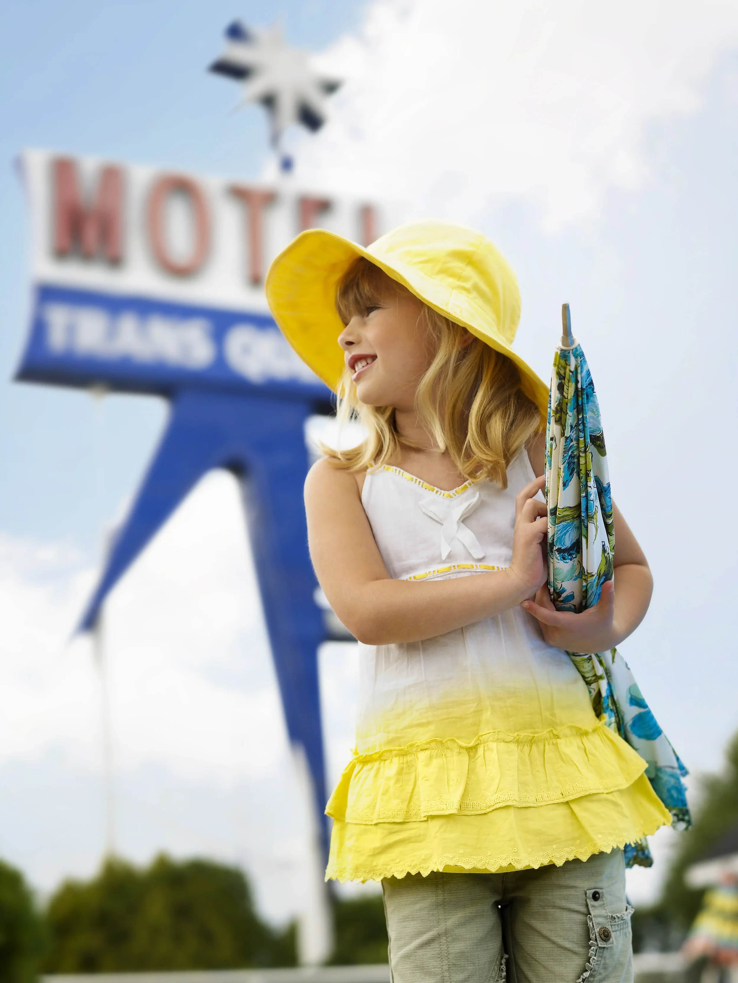 Jeune fille avec capeline et parasol se dirigeant vers la piscine d’un motel américain