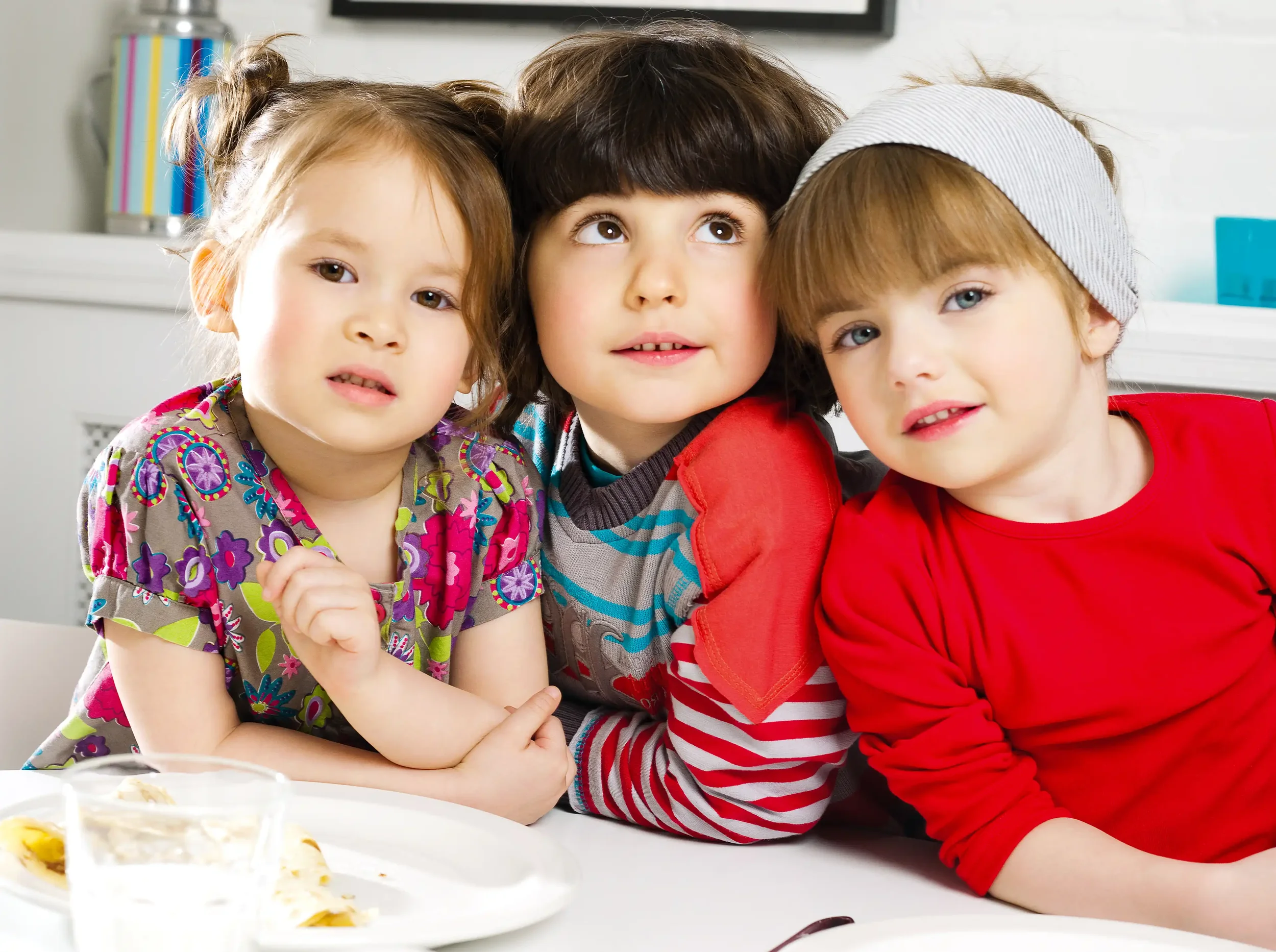 Trois enfants rêveurs autour d’une table illustrant l’imaginaire et le storytelling de marque