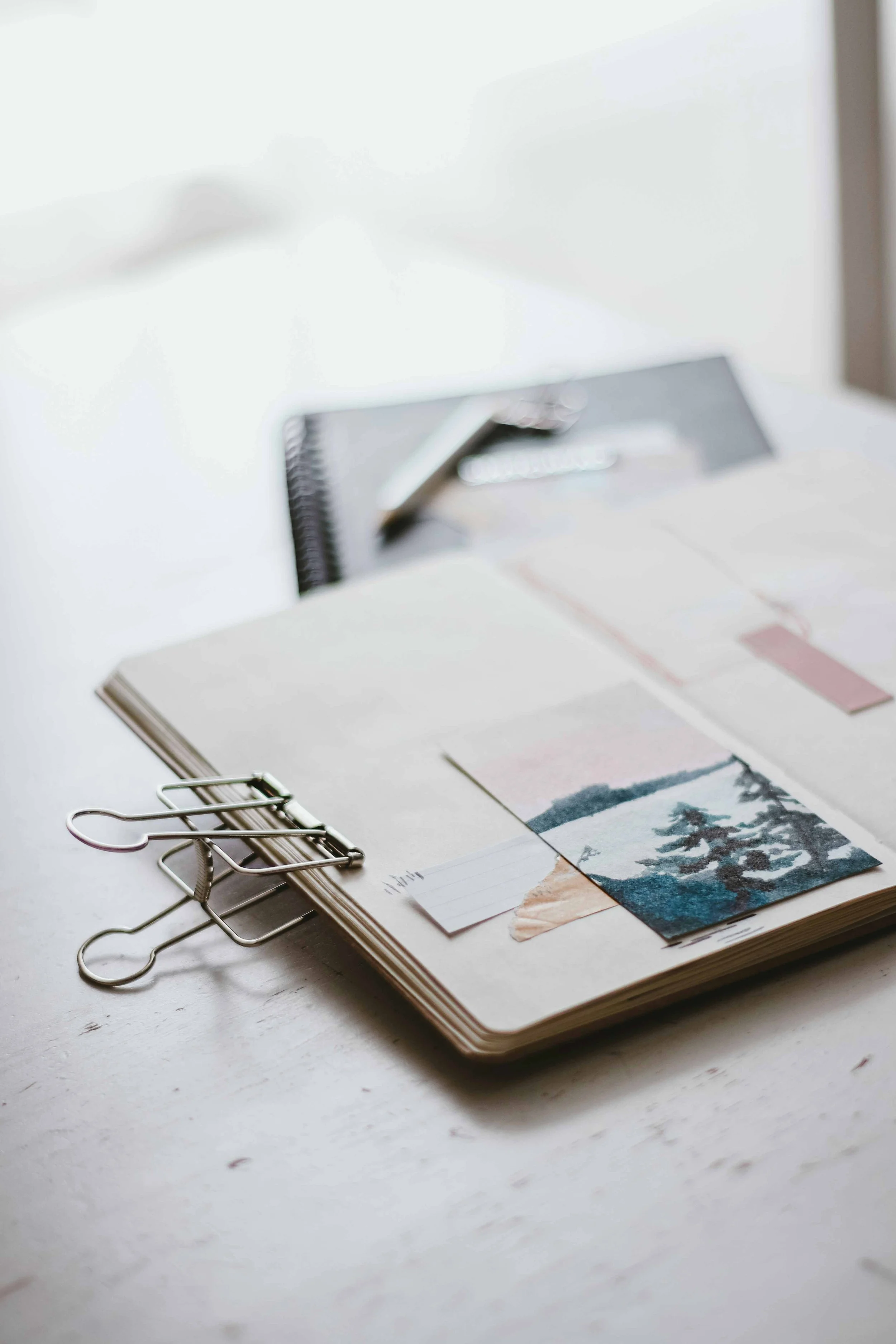 Un carnet ouvert avec des photos et des notes, posé sur une surface blanche, avec des clips et des papiers, lors de la validation d'un editing avec Mathilde Lafargue