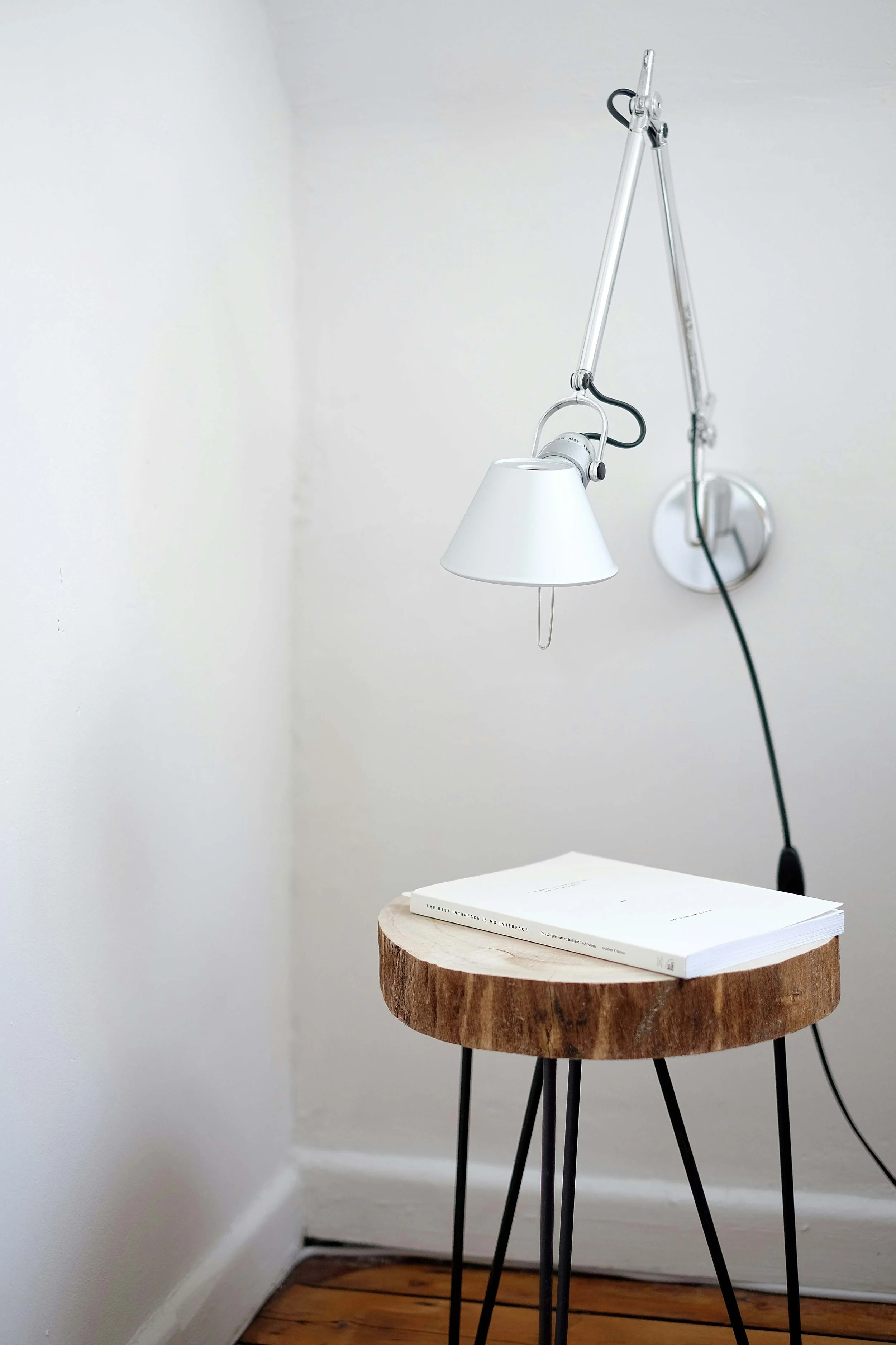 Une lampe de bureau blanche suspendue au plafond au-dessus d'une table en rondins avec un livre blanc dessus, symbolisant la clarté qu'apporte Mathilde Lafargue  aux directeurs marketing et aux dirigeants lors de sa mission en direction artistique