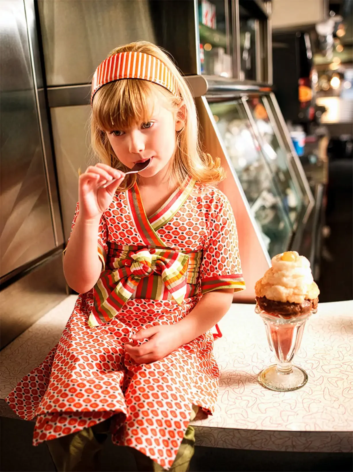 Jeune fille dégustant une glace au comptoir d’un diner américain dans la campagne publicitaire Orchestra