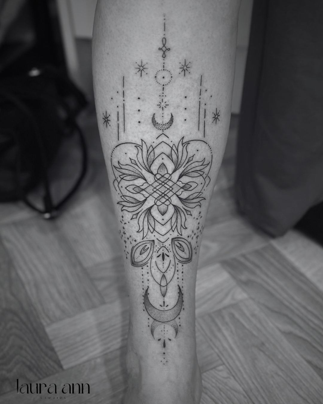 Intricate geometric tattoo on calf, featuring floral and abstract designs with crescent moons and stars.
