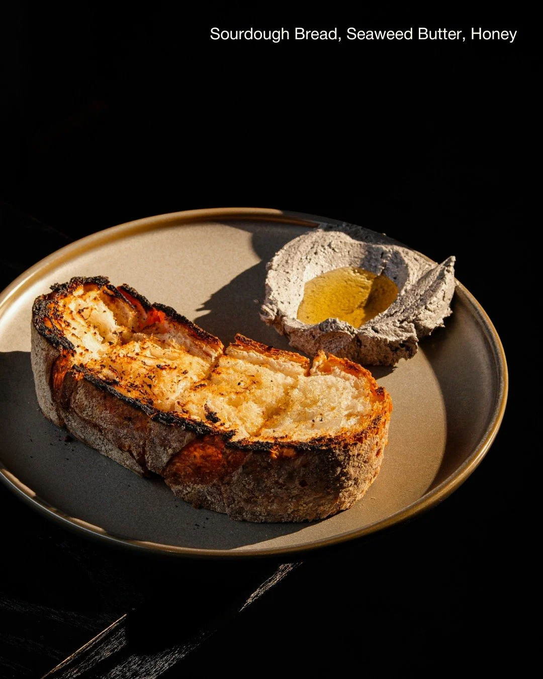 Our 𝗦𝗼𝘂𝗿𝗱𝗼𝘂𝗴𝗵 𝗕𝗿𝗲𝗮𝗱, 𝗦𝗲𝗮𝘄𝗲𝗲𝗱 𝗕𝘂𝘁𝘁𝗲𝗿, 𝗛𝗼𝗻𝗲𝘆 proves that simplicity can set the perfect tone for an evening.
Warm sourdough arrives with the crackle of the oven still lingering on its crust. Seaweed butter lends savoury