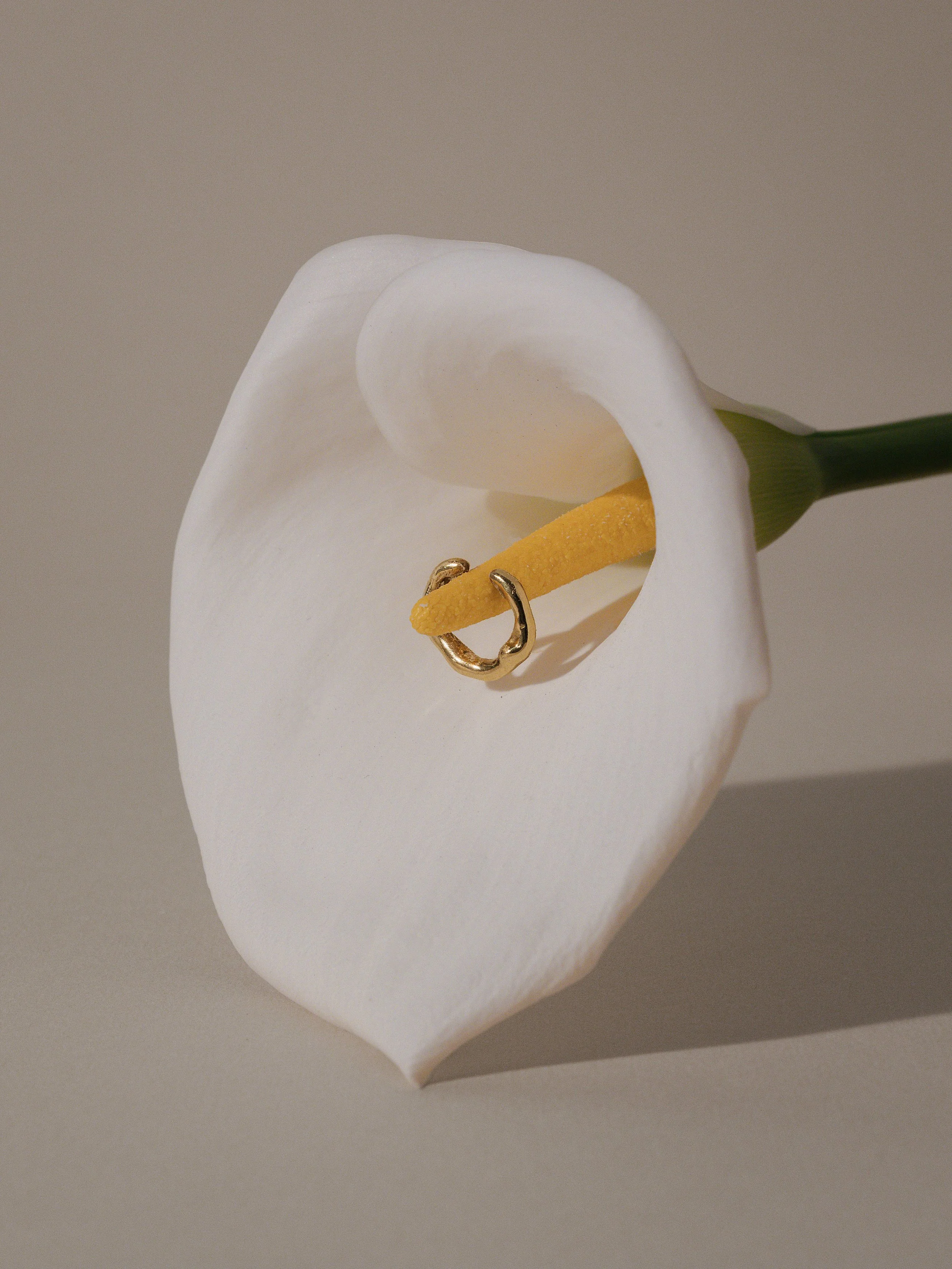 Earcuff posato su un fiore di calla bianco e giallo.