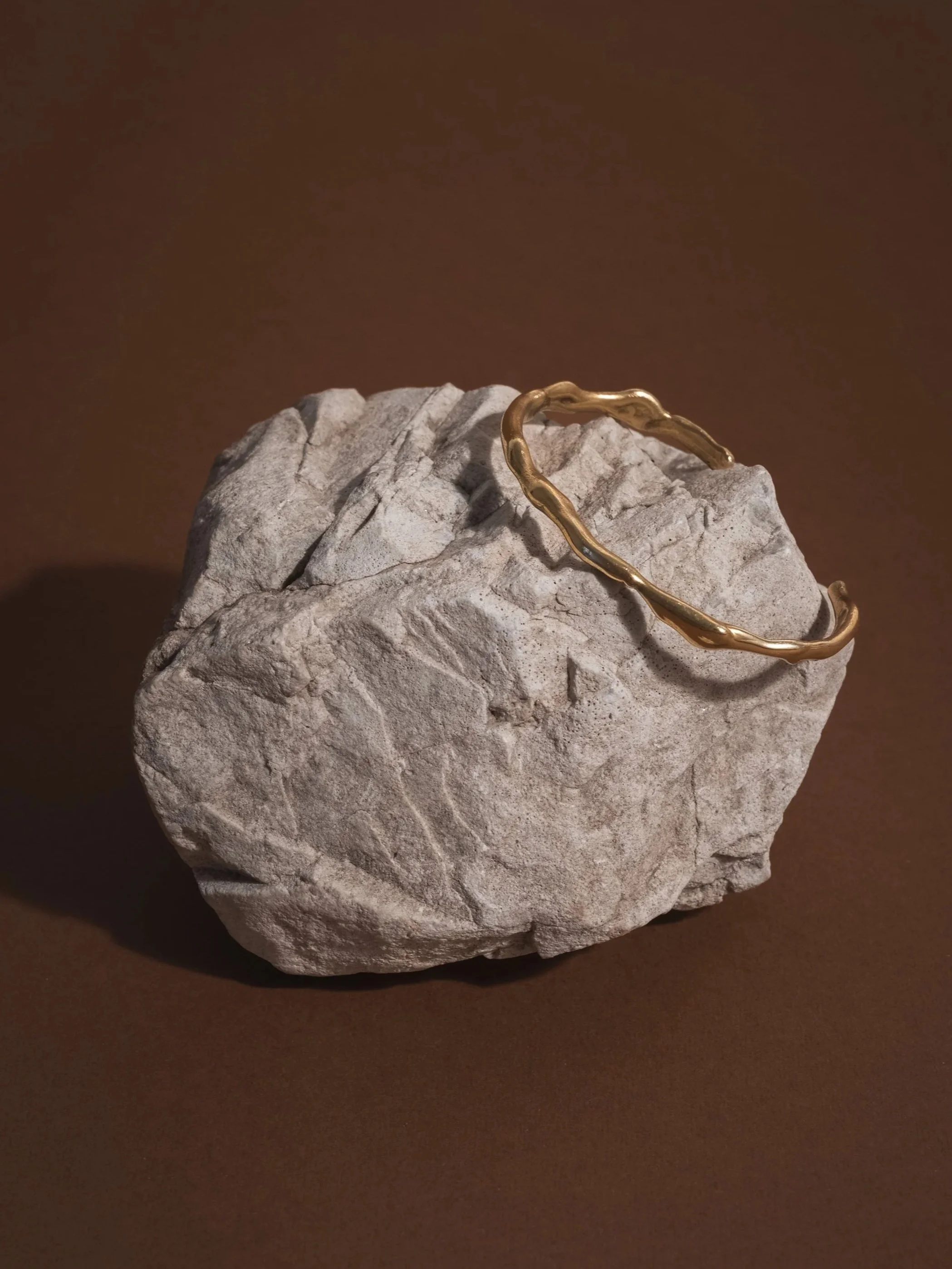 bracciale ottone appoggiato su pietra con fondo marrone