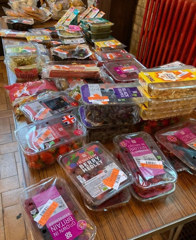 A variety of packed fresh berries and other produce on a wooden table at a grocery store, including strawberries, raspberries, blackberries, and cherry medley.