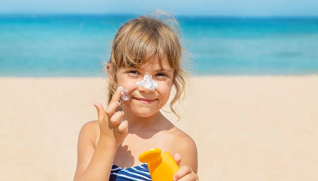 Young girl putting sunscreen on her face