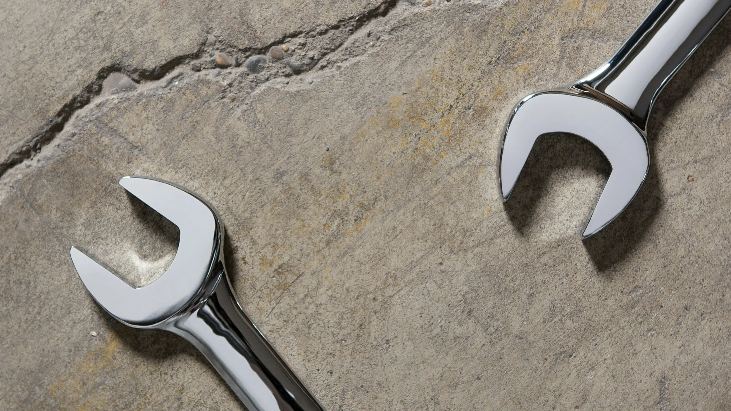 Two open-end wrenches on concrete surface