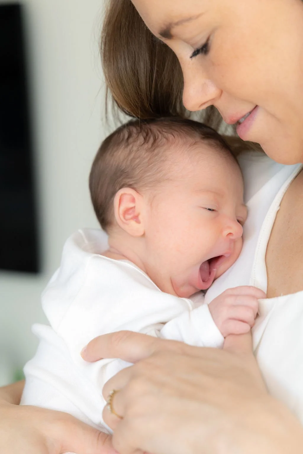 Die Mutter hält ihr Baby im Arm, und es gähnt..jpg