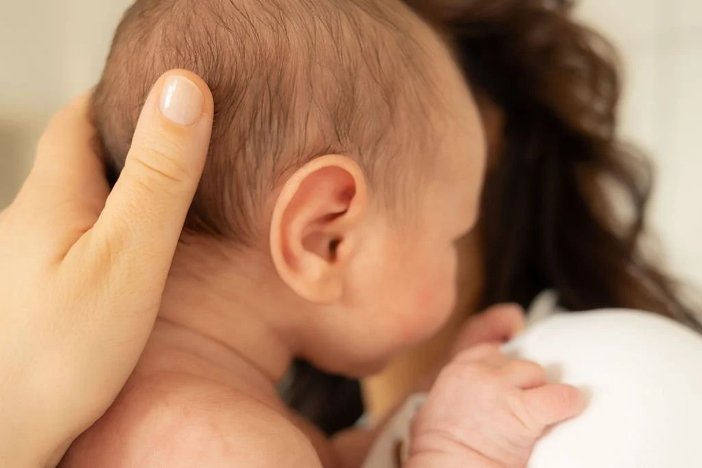 Die Mutter hält das Baby am Kopf fest und trägt es auf den Armen..jpg
