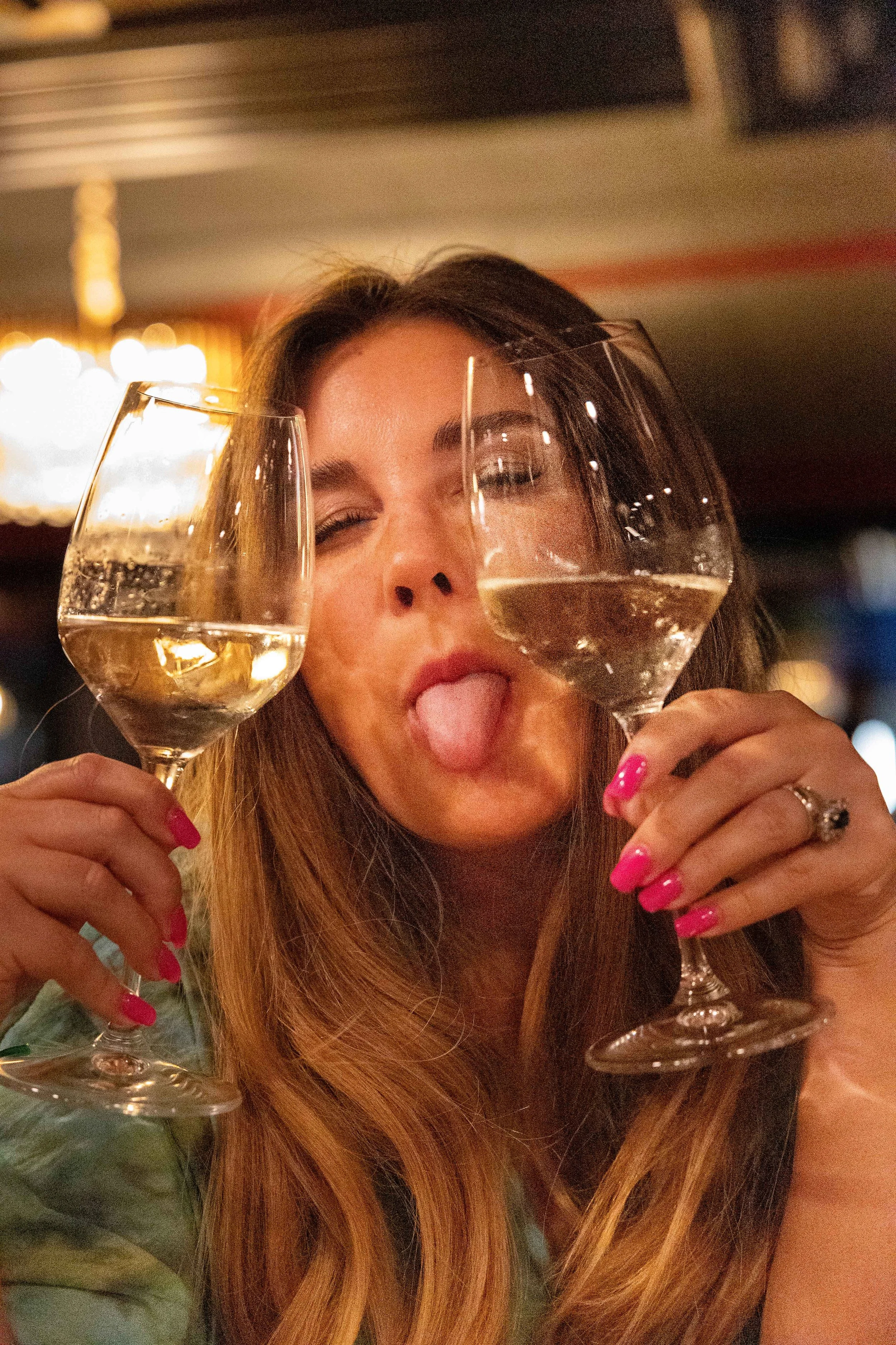 Eine Frau hält zwei Gläser und schneidet Grimassen..jpg