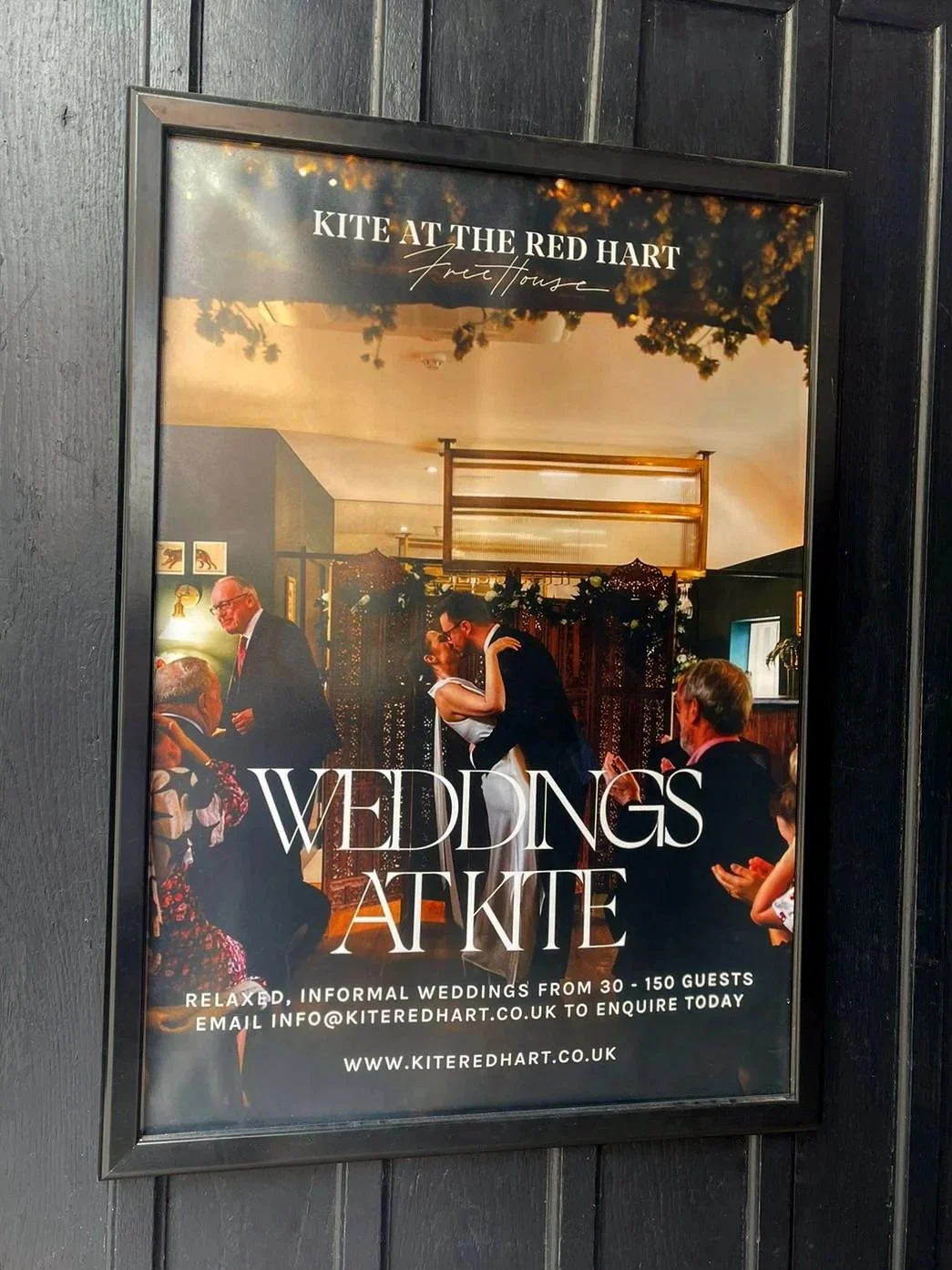 A poster advertising weddings at Kite at the Red Hart, with a photo of a wedding reception showing people dancing and dressed in formal attire in a decorated venue.