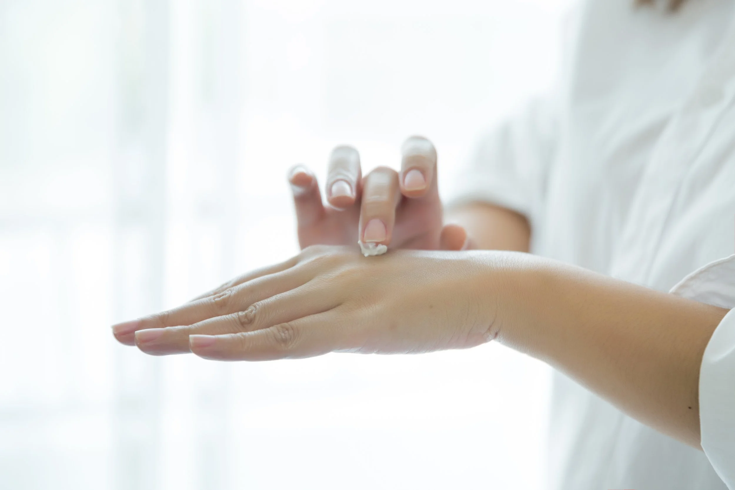 Person trägt Lotion auf Hand auf.