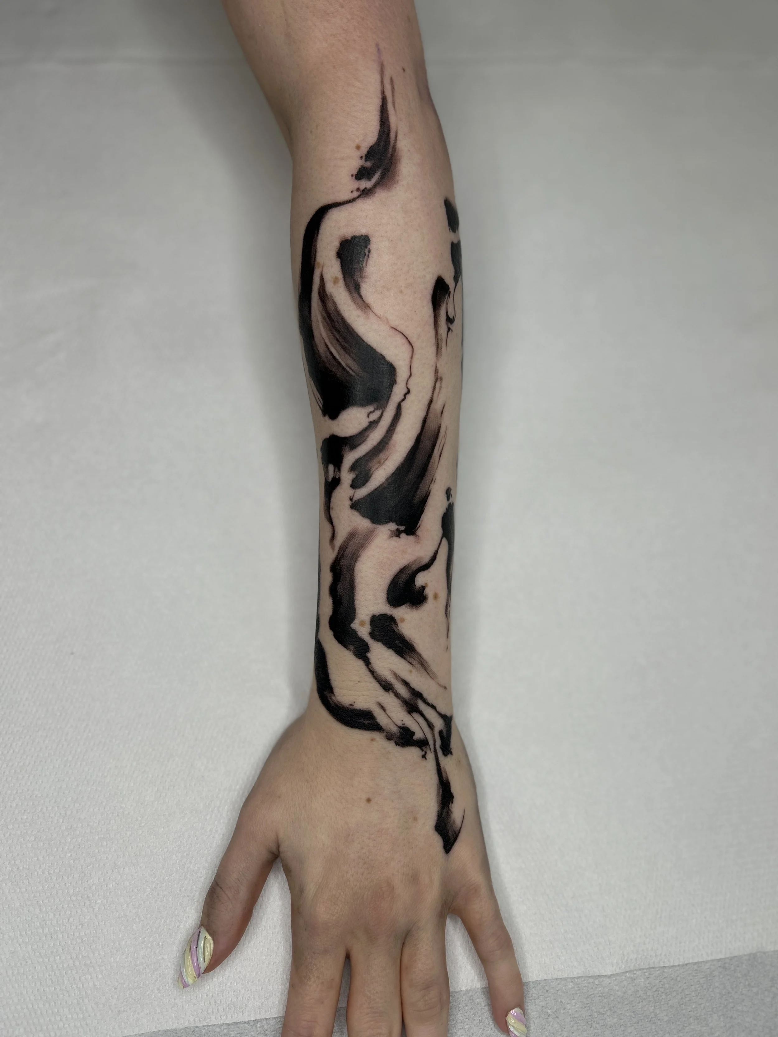 Tatouage abstrait noir sur le bras et la main d'une personne