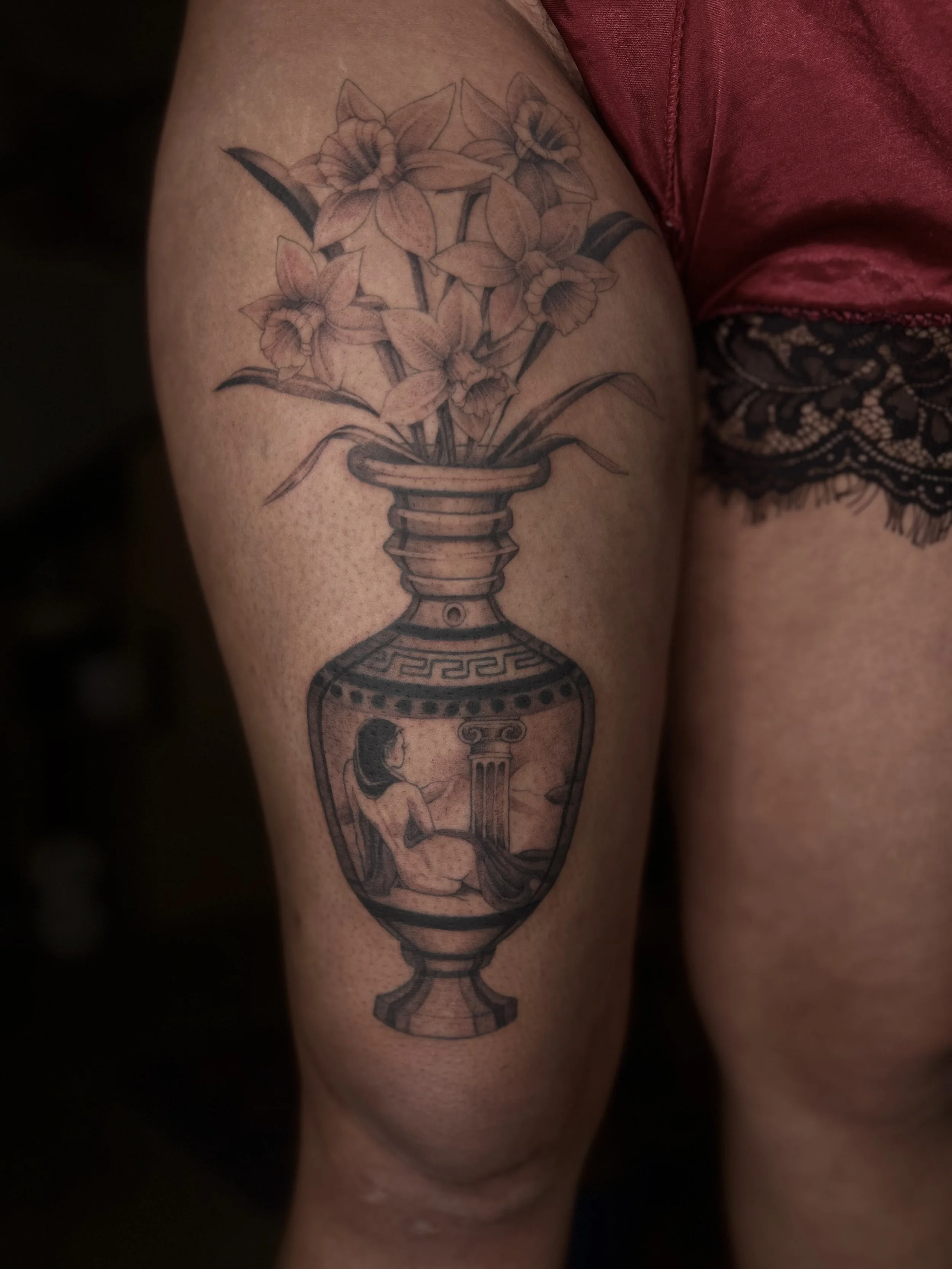 Tatouage représentant un vase avec des fleurs au sommet, et une femme assise à l'intérieur du vase.