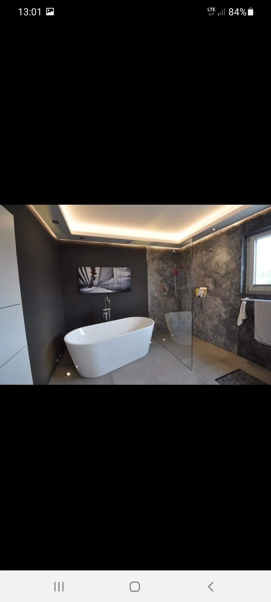 Modernes Badezimmer mit freistehender Badewanne, begehbarer Dusche mit Trennwand, dunklen Wänden und einem Fenster.