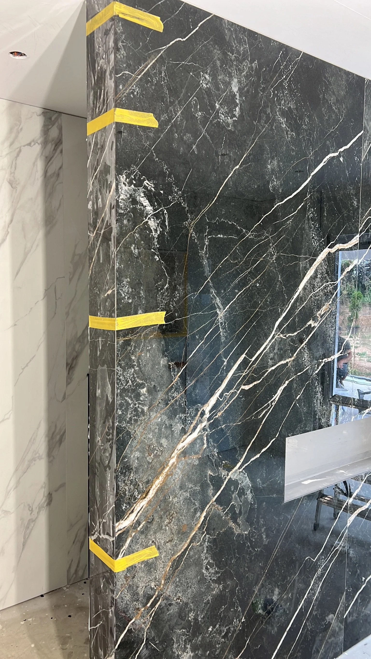 Schwarze Marmorplatte mit goldenen und weißen Aderungen, Teil eines Innenraumdesigns, mit Klebeband an den Rändern