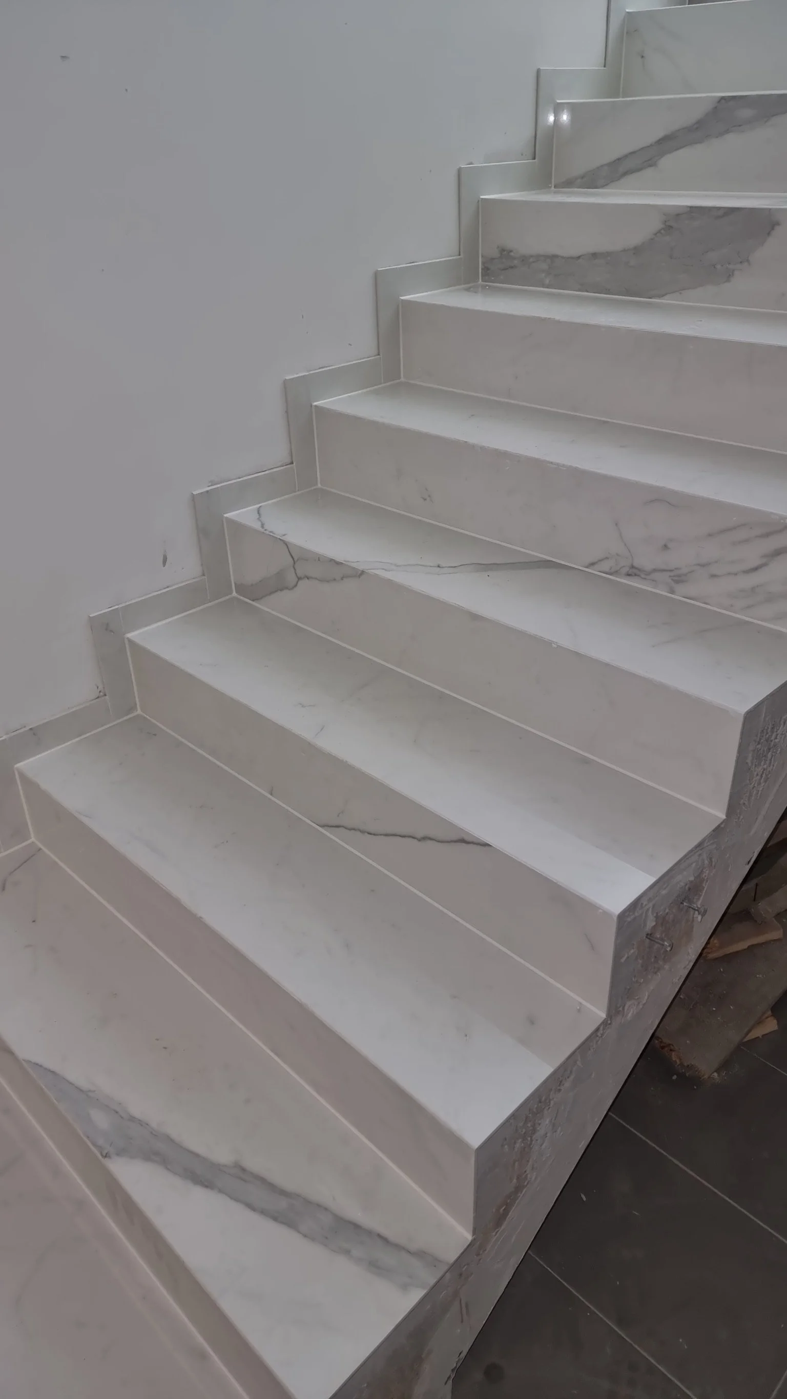 Weiße Marmorstufen mit grauen Adern in einem modernen Treppenhaus.