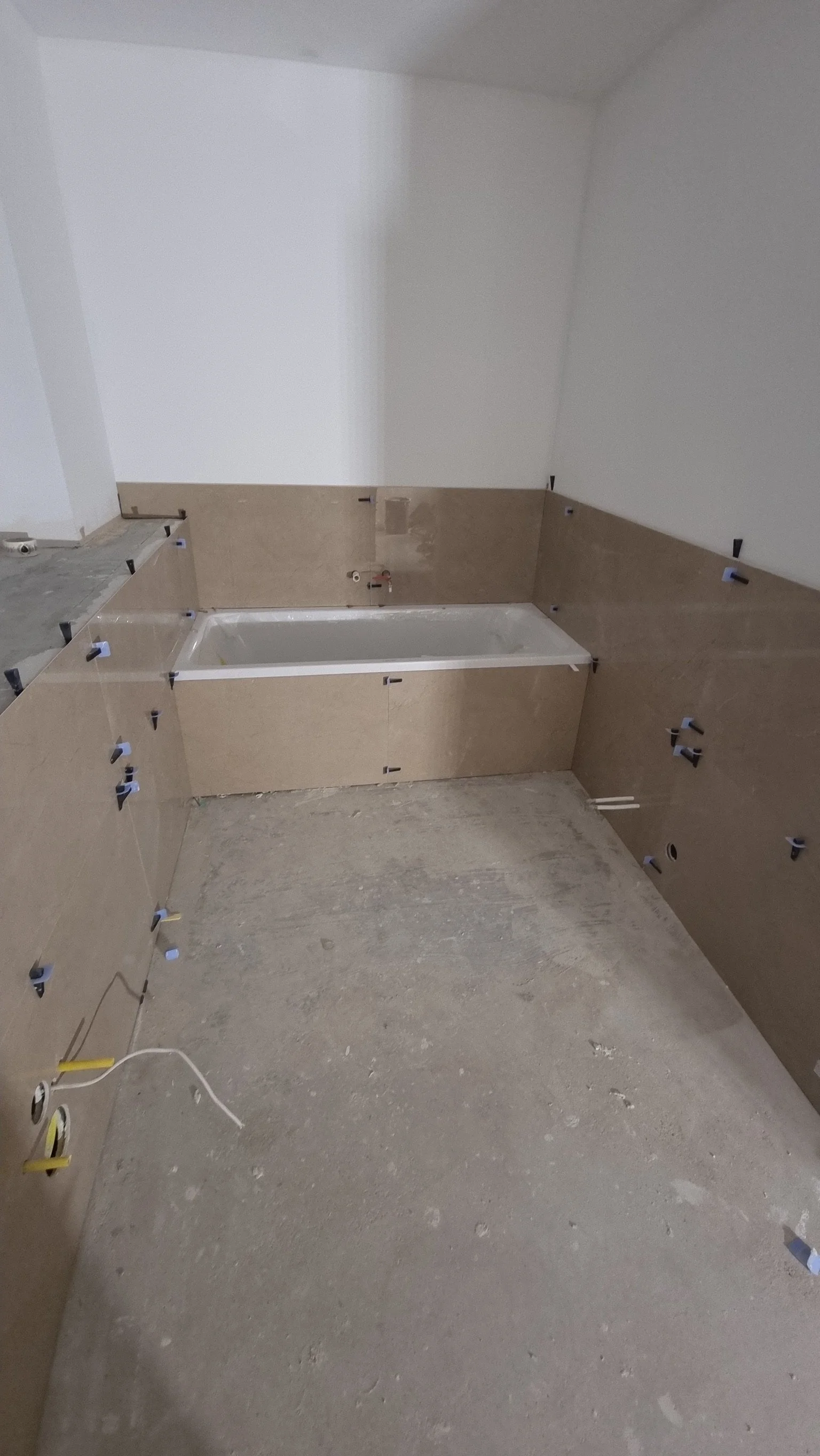 Badezimmer im Bau mit Wanneninstallationen und Fliesenarbeiten, die noch erledigt werden müssen.