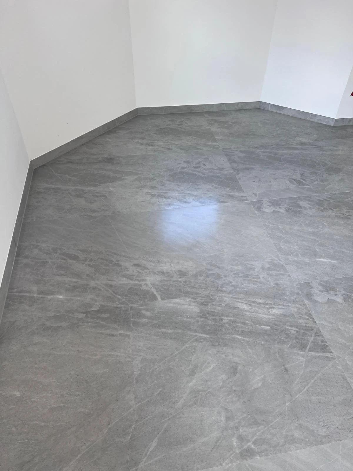 Brandneuer Raum mit grauem Marmorboden und weißen Wänden.