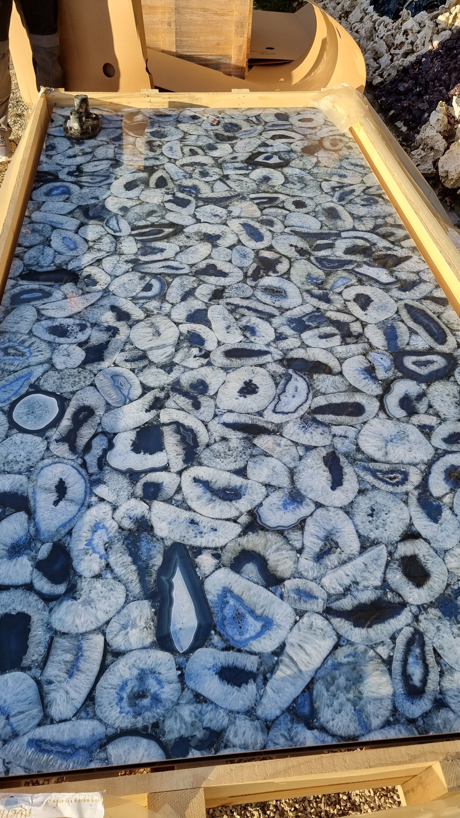 Nahaufnahme eines geologischen Musters mit an Polished Geoden erinnernden Quarz- und Mineralienbrocken in Wasser eingelagert.