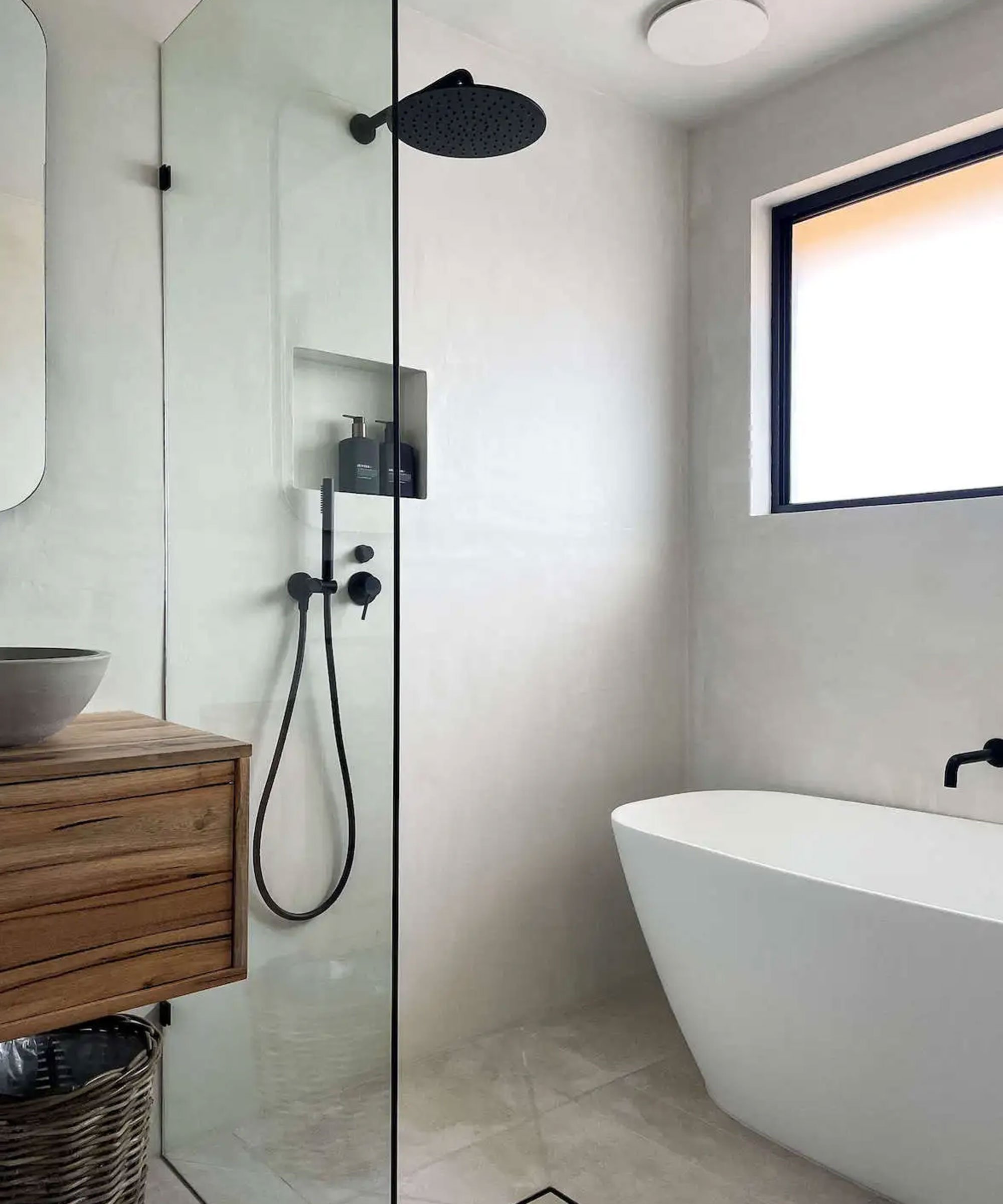 Moderner Badezimmer mit freistehender Badewanne, Dusche mit Regenkopf, Holzwaschbecken und kleinem Wandschrank, großes Fenster für viel Tageslicht.