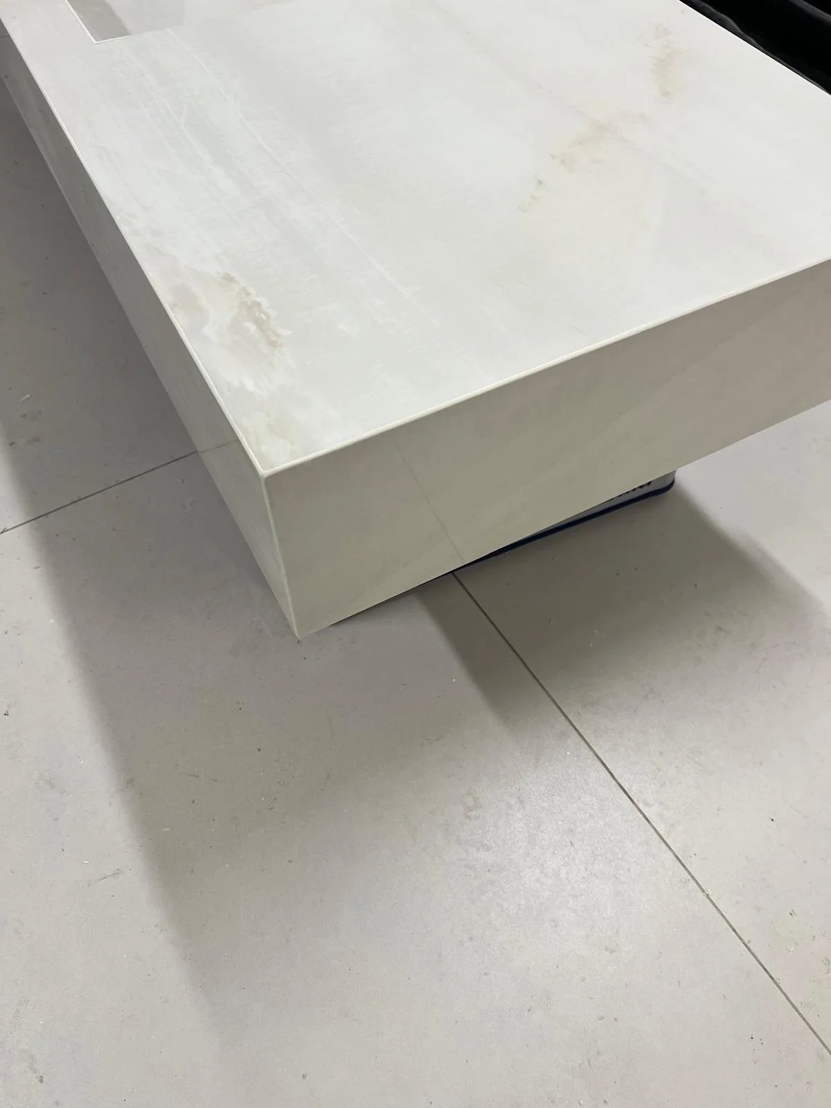 Ein weißer, glänzender Tisch auf hellen Fliesenboden.