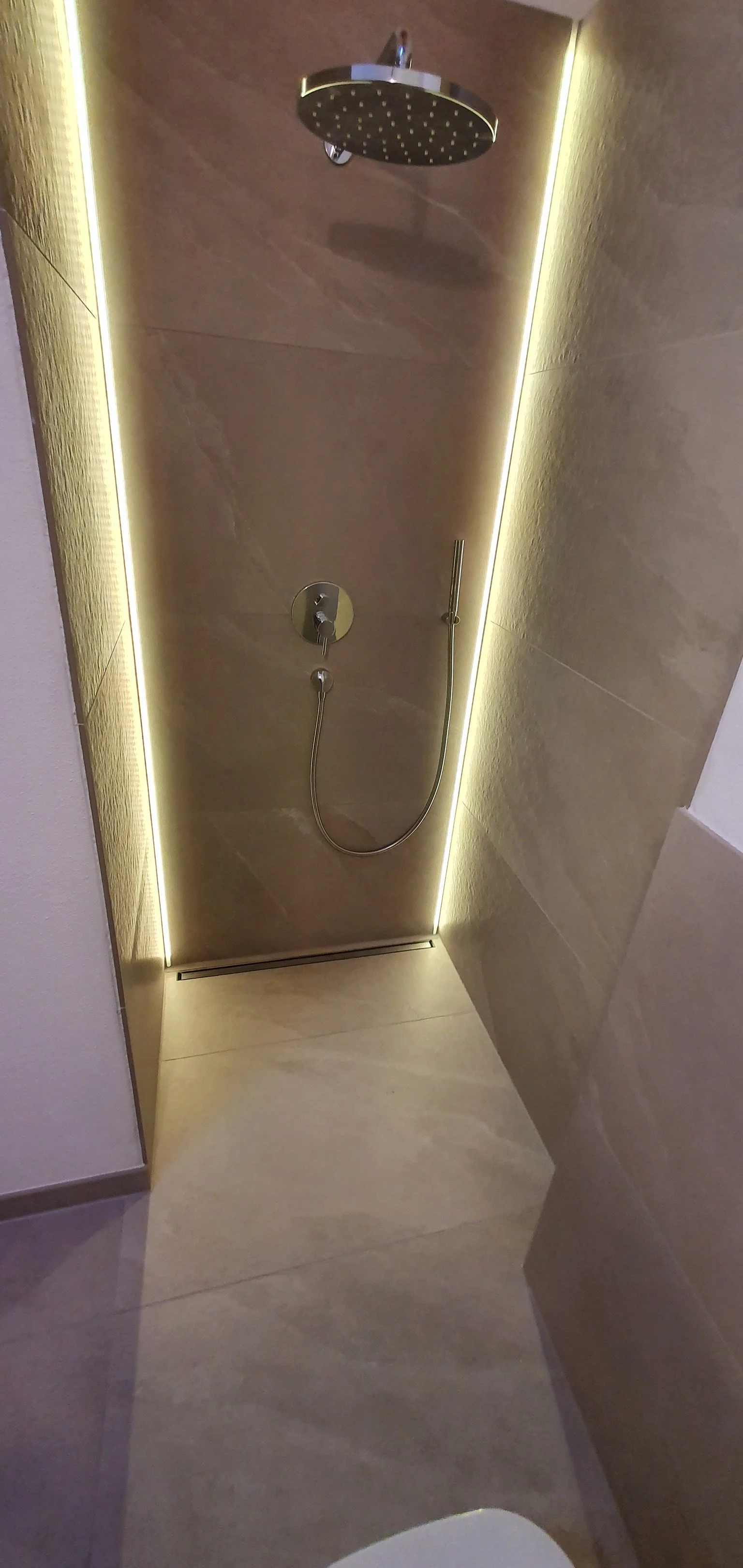 Moderne Dusche mit dunklem Duschkopf, Handbrause und LED-Beleuchtung in einer Badewanne oder Duschkabine.