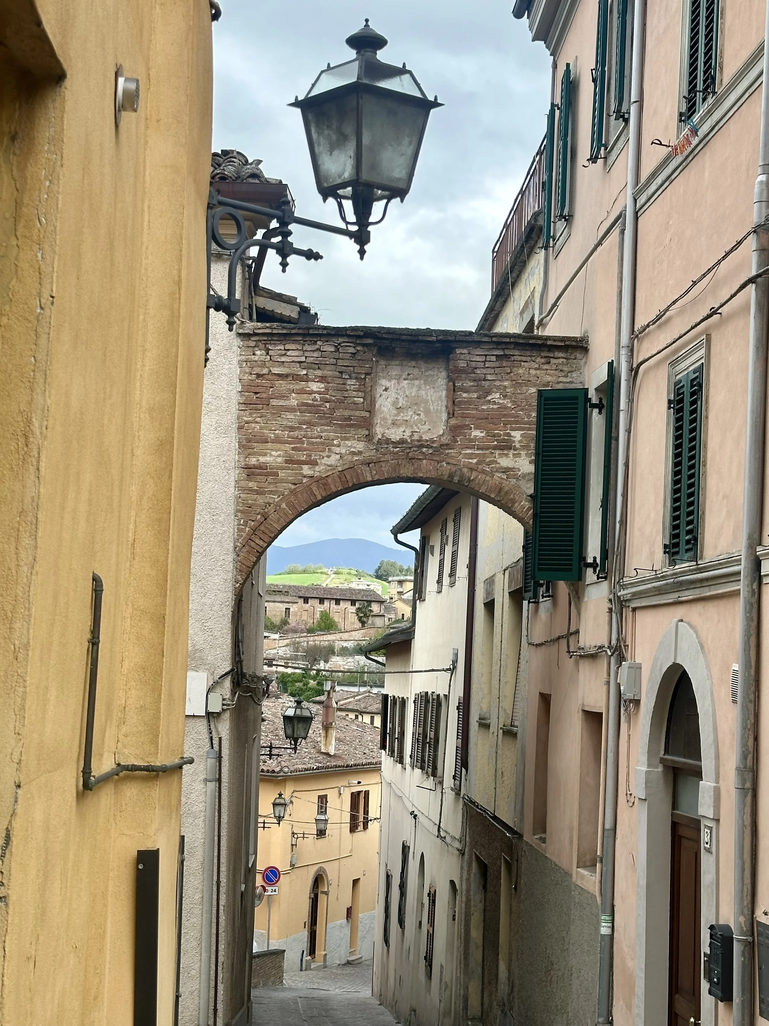 image of he narrow streets of fabriano and some old lights and the mountains in the background