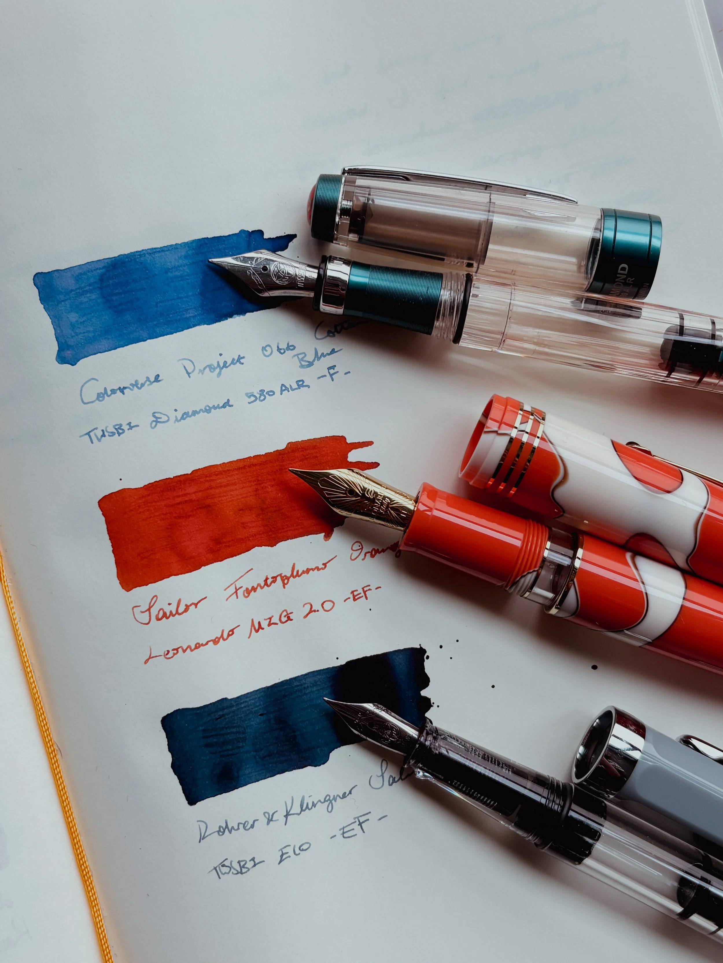 Three fountain pens with ink swatches.