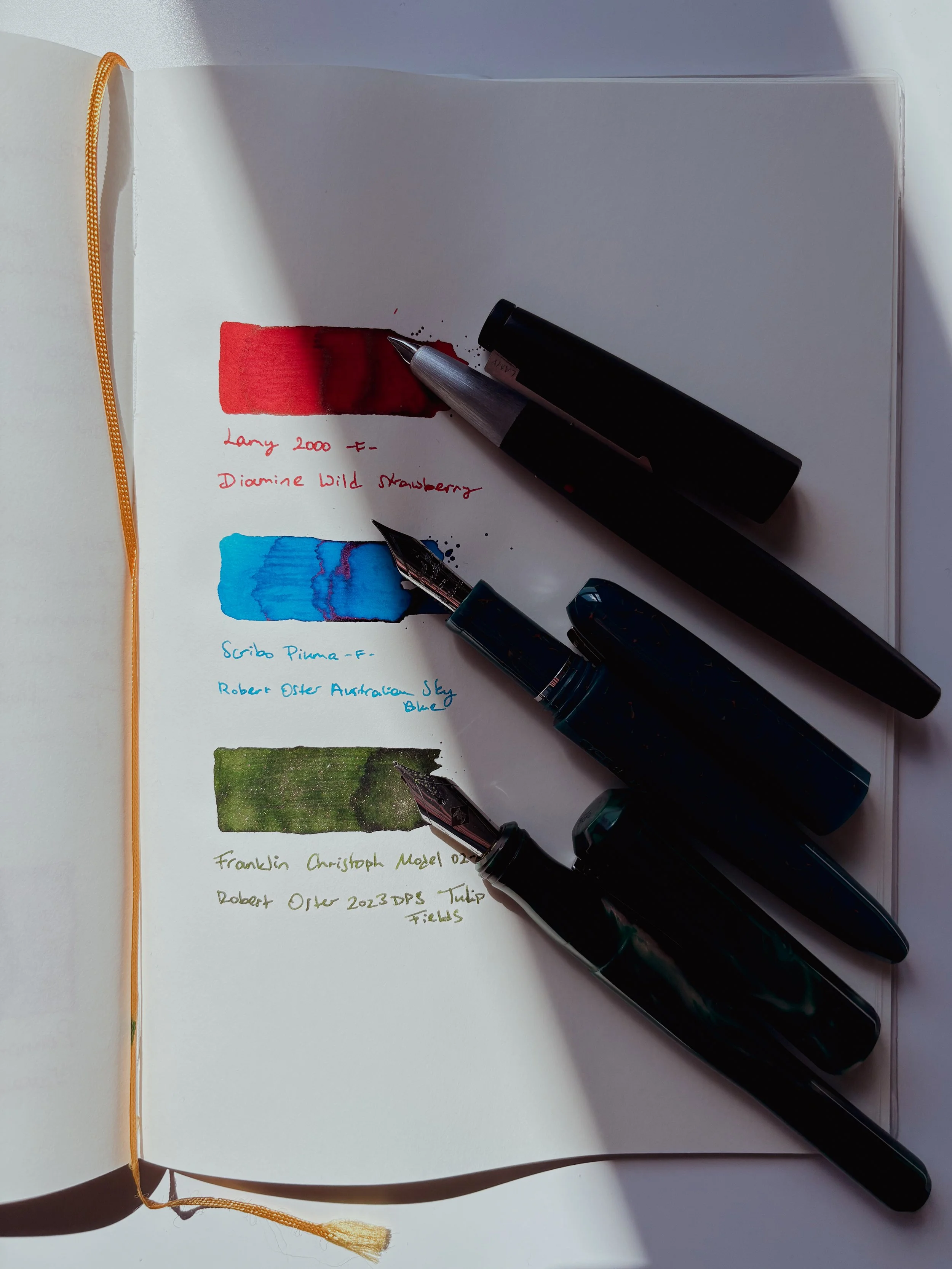 Three fountain pens with ink swatches.