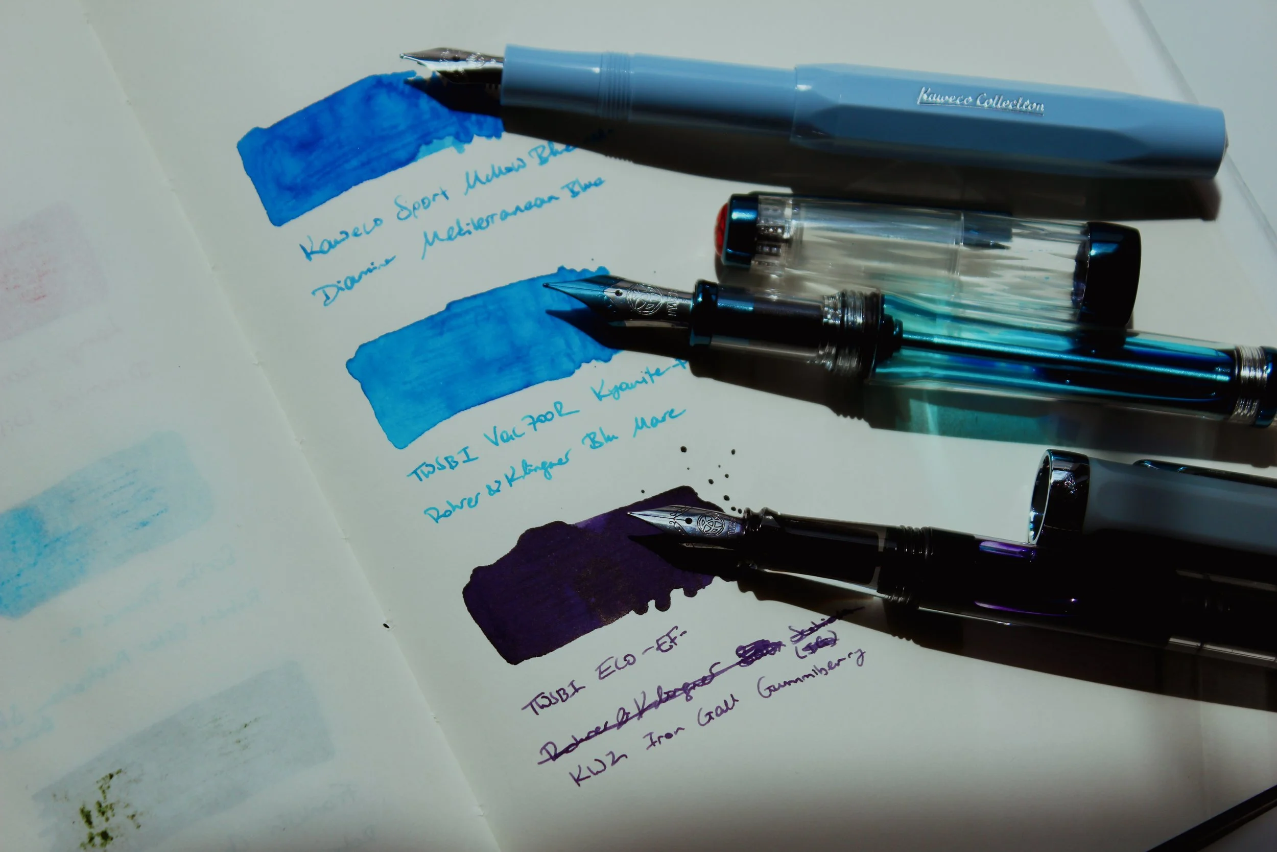 Three fountain pens with ink swatches.