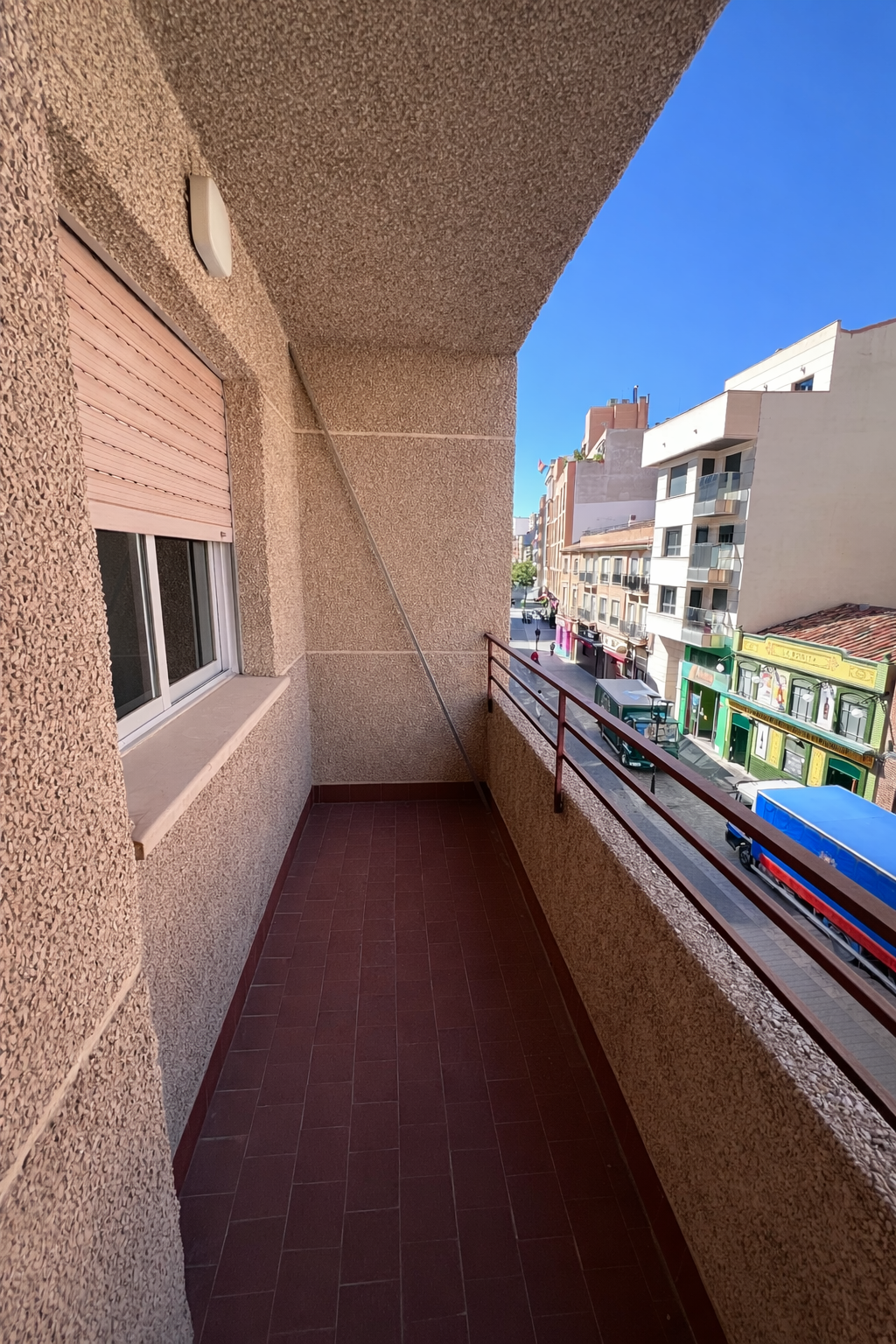 Vista urbana desde balcón soleado.png