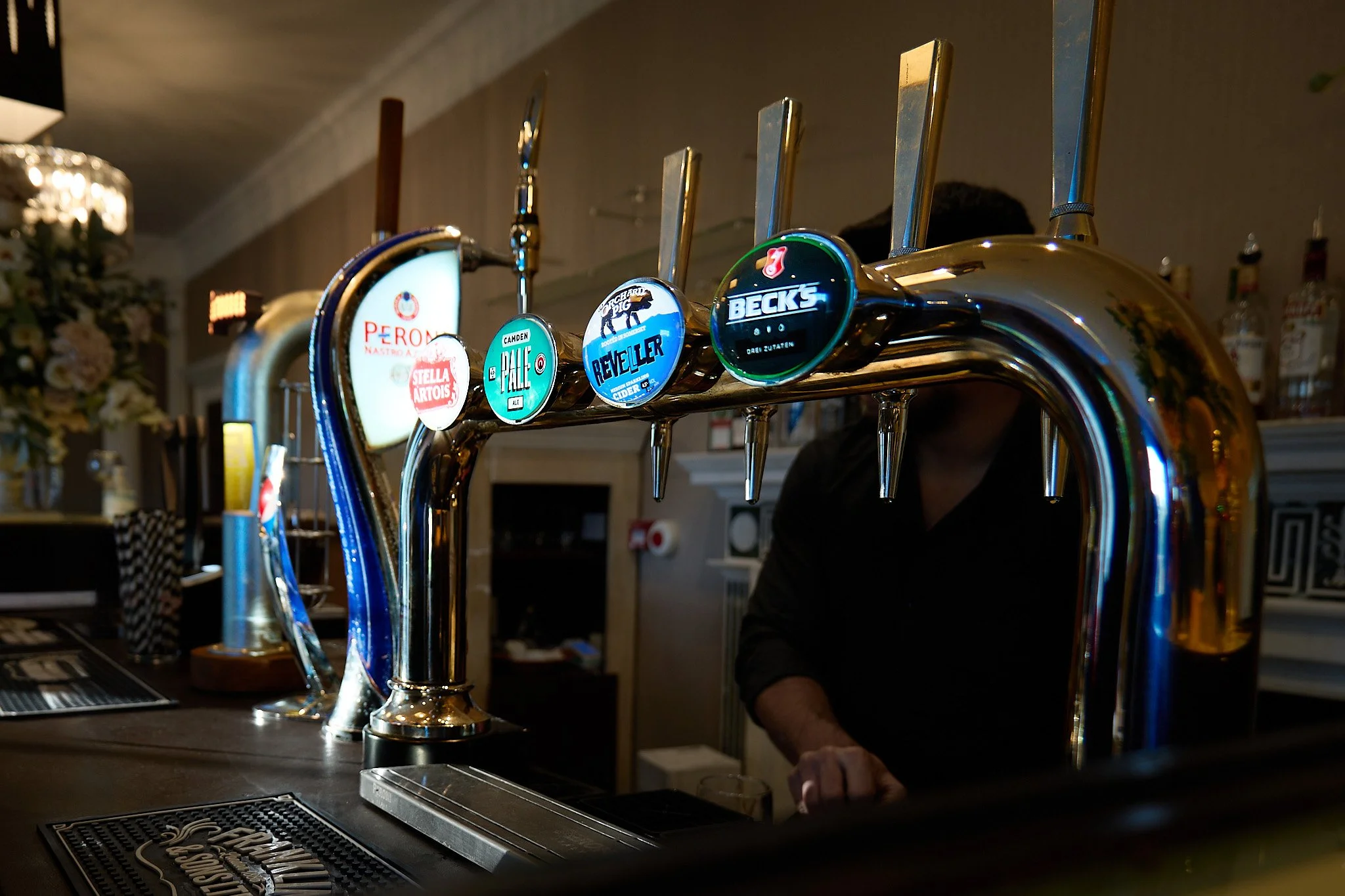 View along a pub bar showing the illuminated beer pumps.