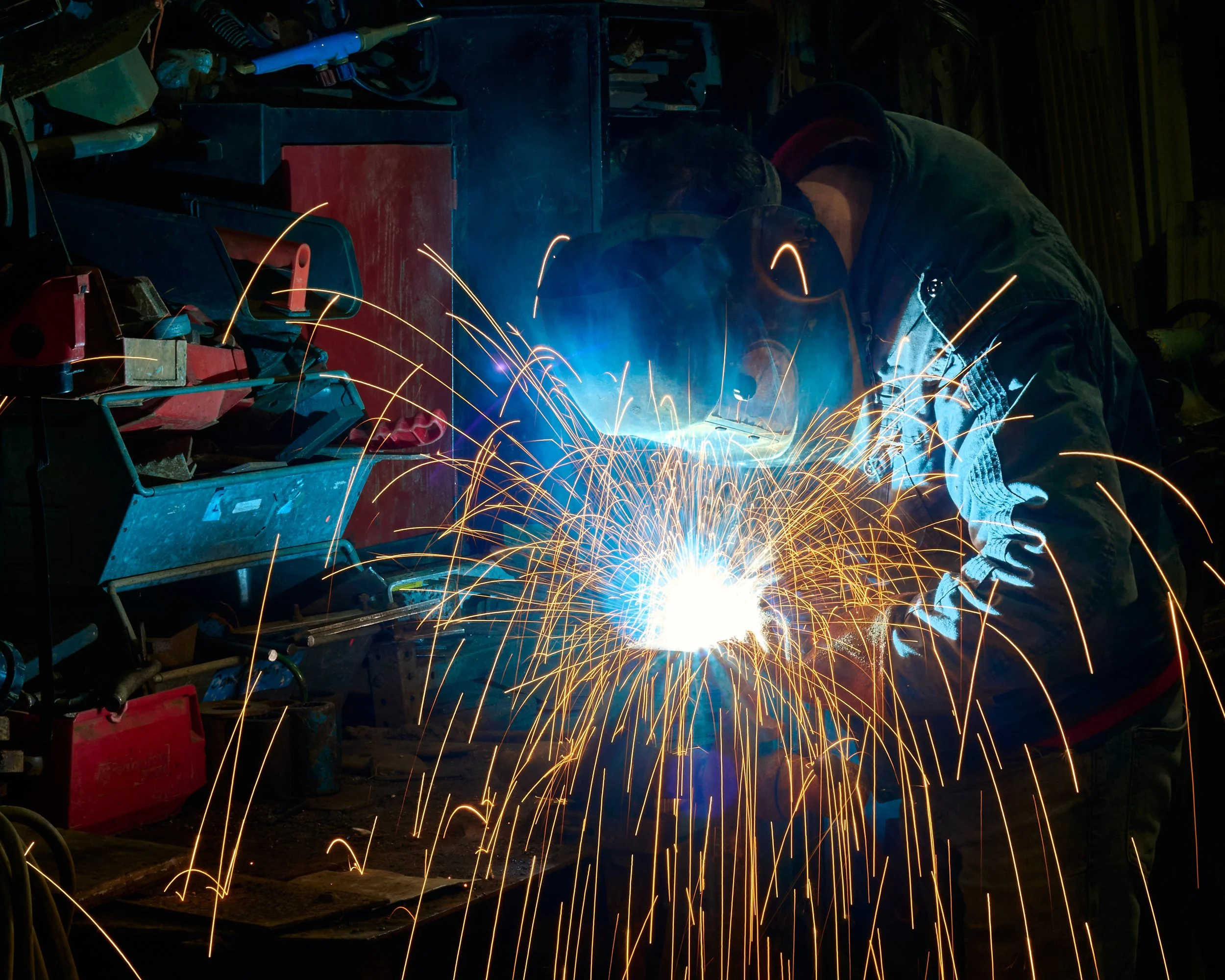 Environmental portrait of a welder fabricating steel with sparks 