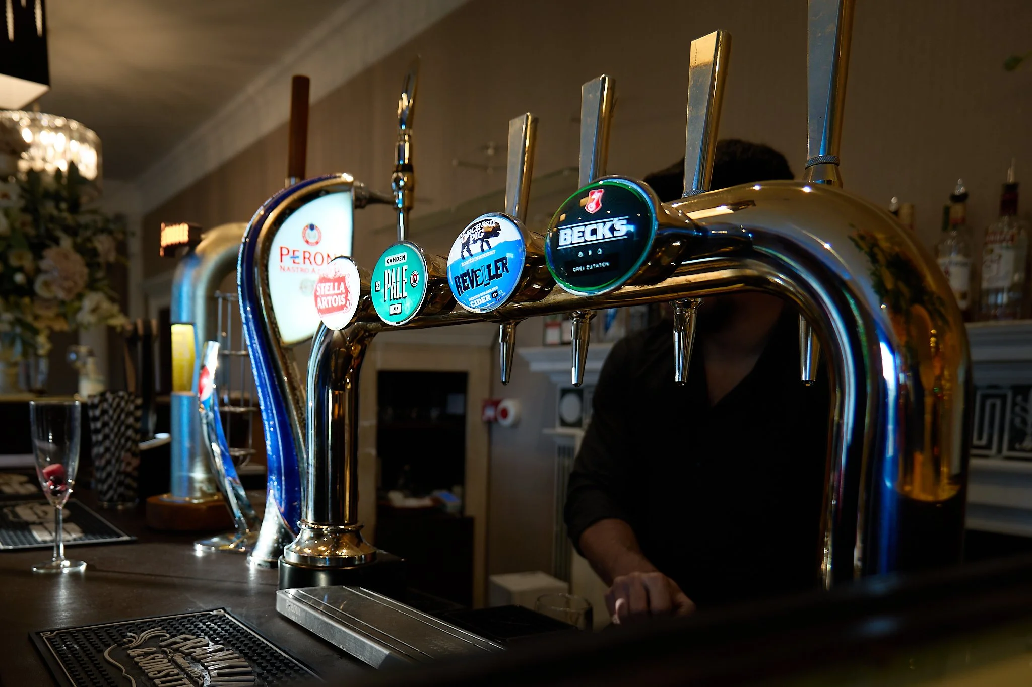 View along a pub bar showing the illuminated beer pumps.