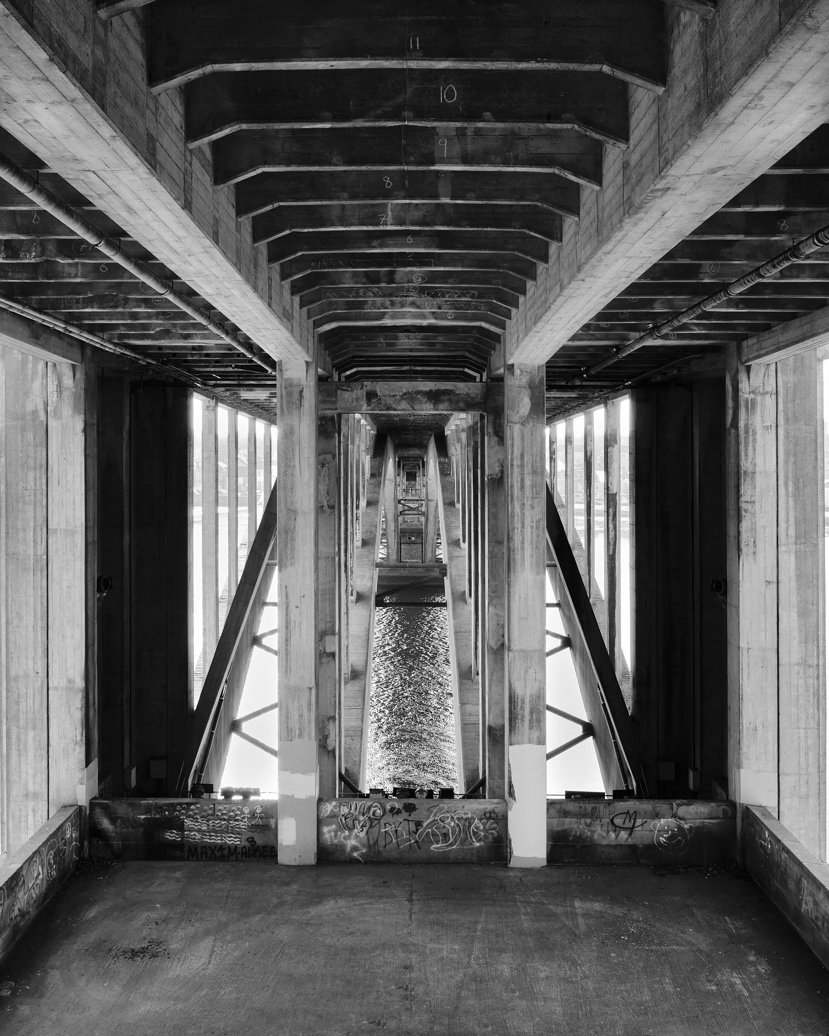 Black and white high contrast architectural photograph of the underside of a bridge demonstrating its geometric qualities.