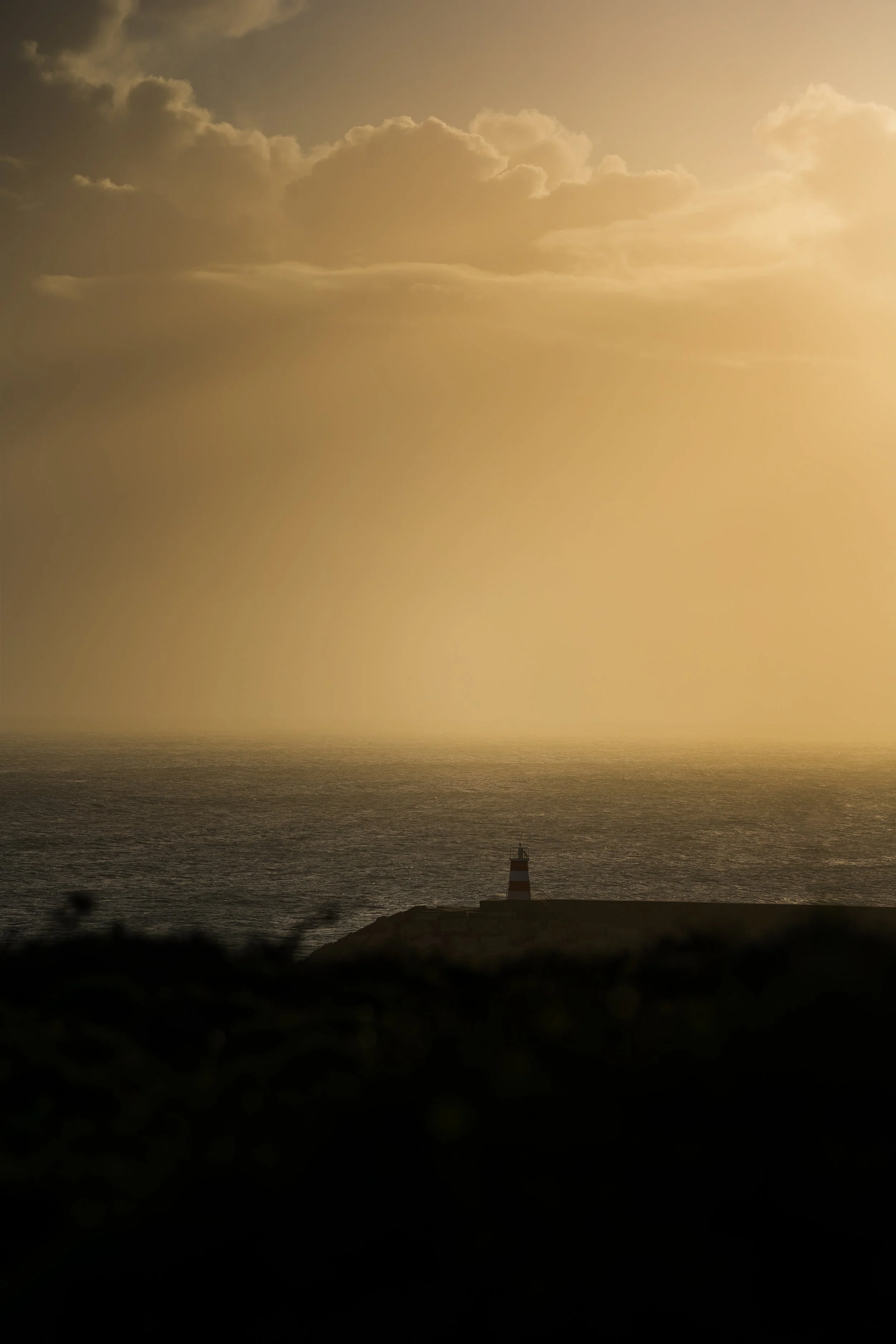 Phare au bord de la mer sous un ciel nuageux doré au crépuscule
