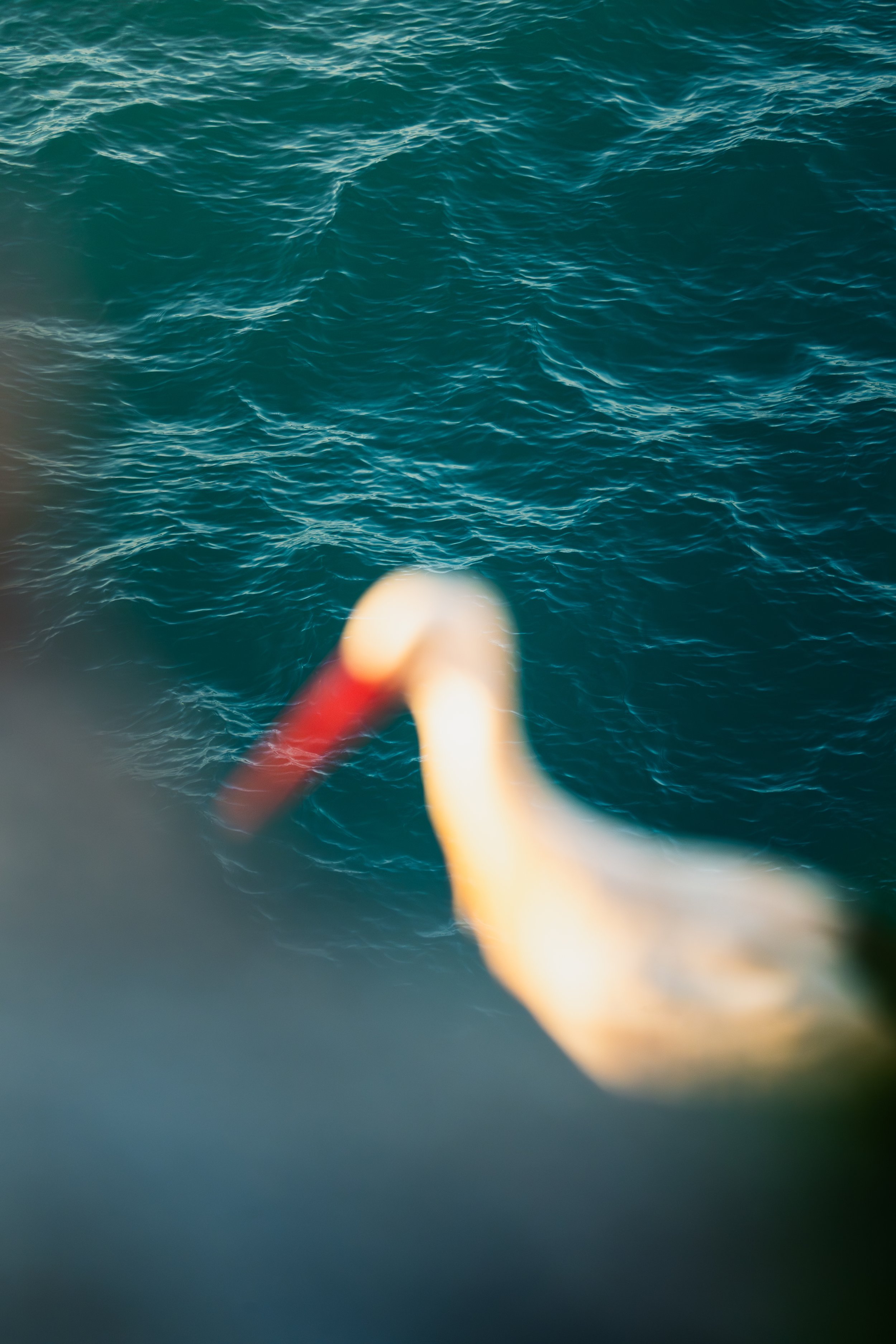 Une mer avec des vagues turquoise, floue en bas avec un câble rouge et une boucle jaune en premier plan.